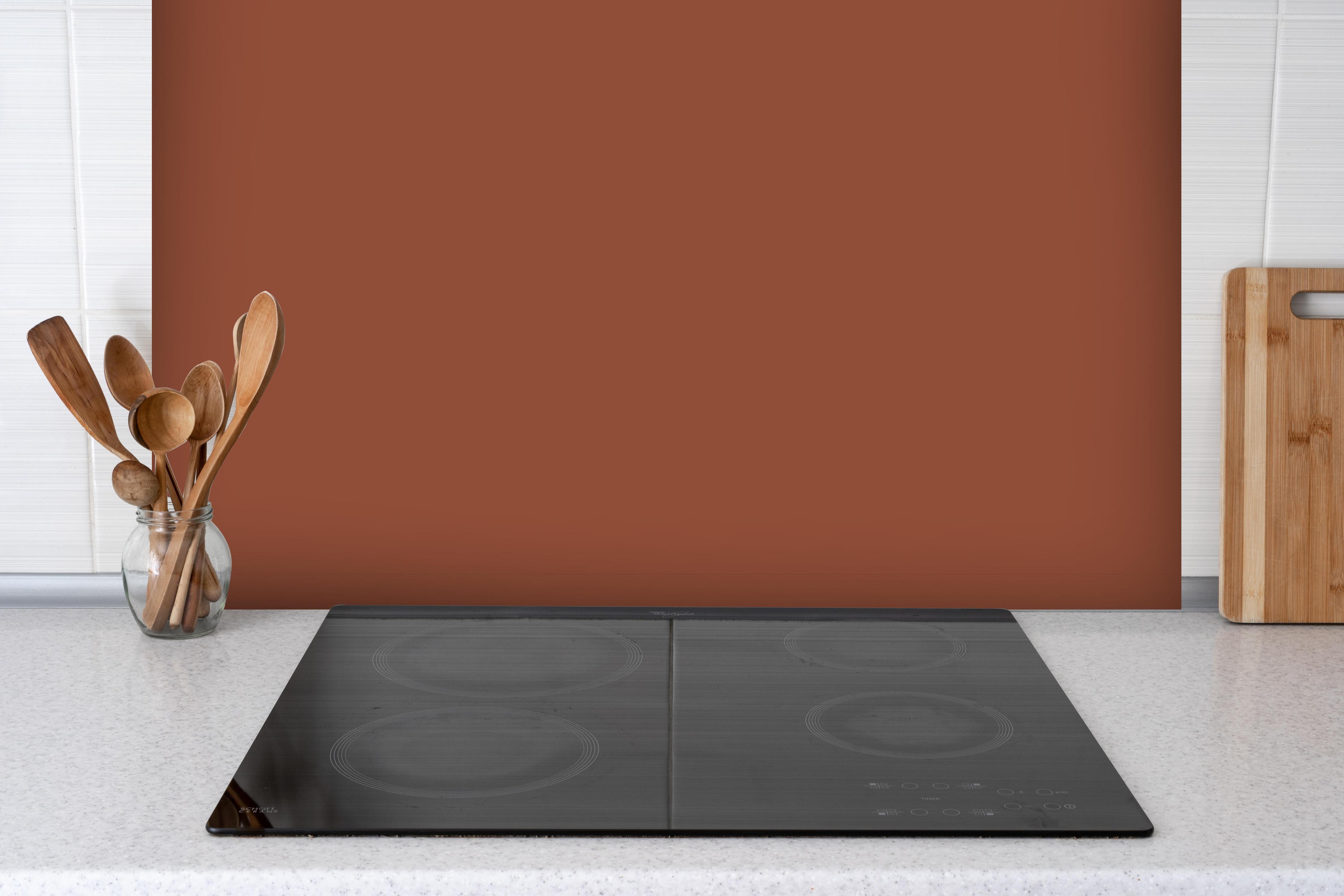 Spritzschutz - RAL 8004 (Kupferbraun) hinter einem Cerankochfeld zwischen Holz-Kochutensilien