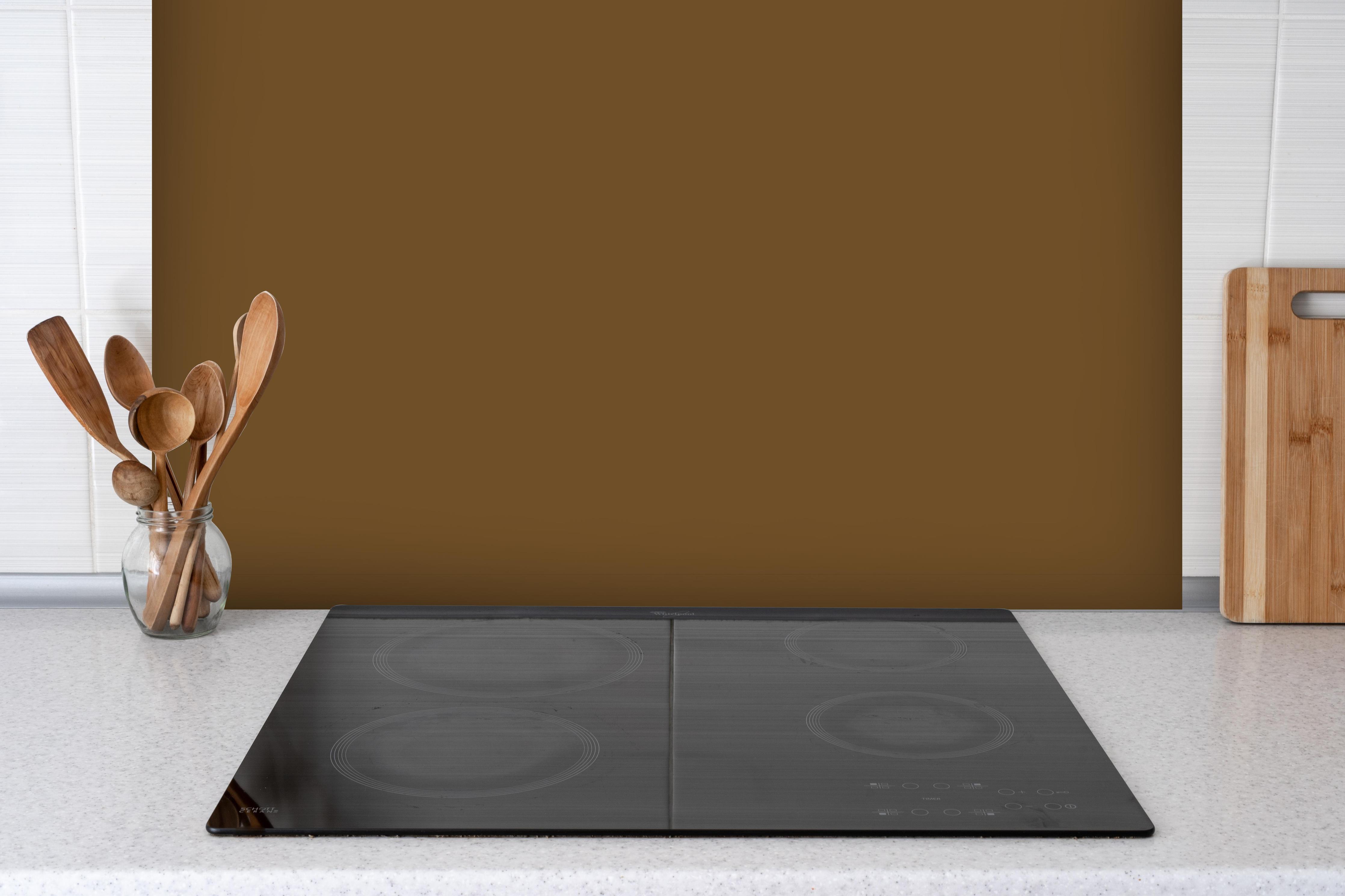 Spritzschutz - RAL 8008 (Olivbraun) hinter einem Cerankochfeld zwischen Holz-Kochutensilien