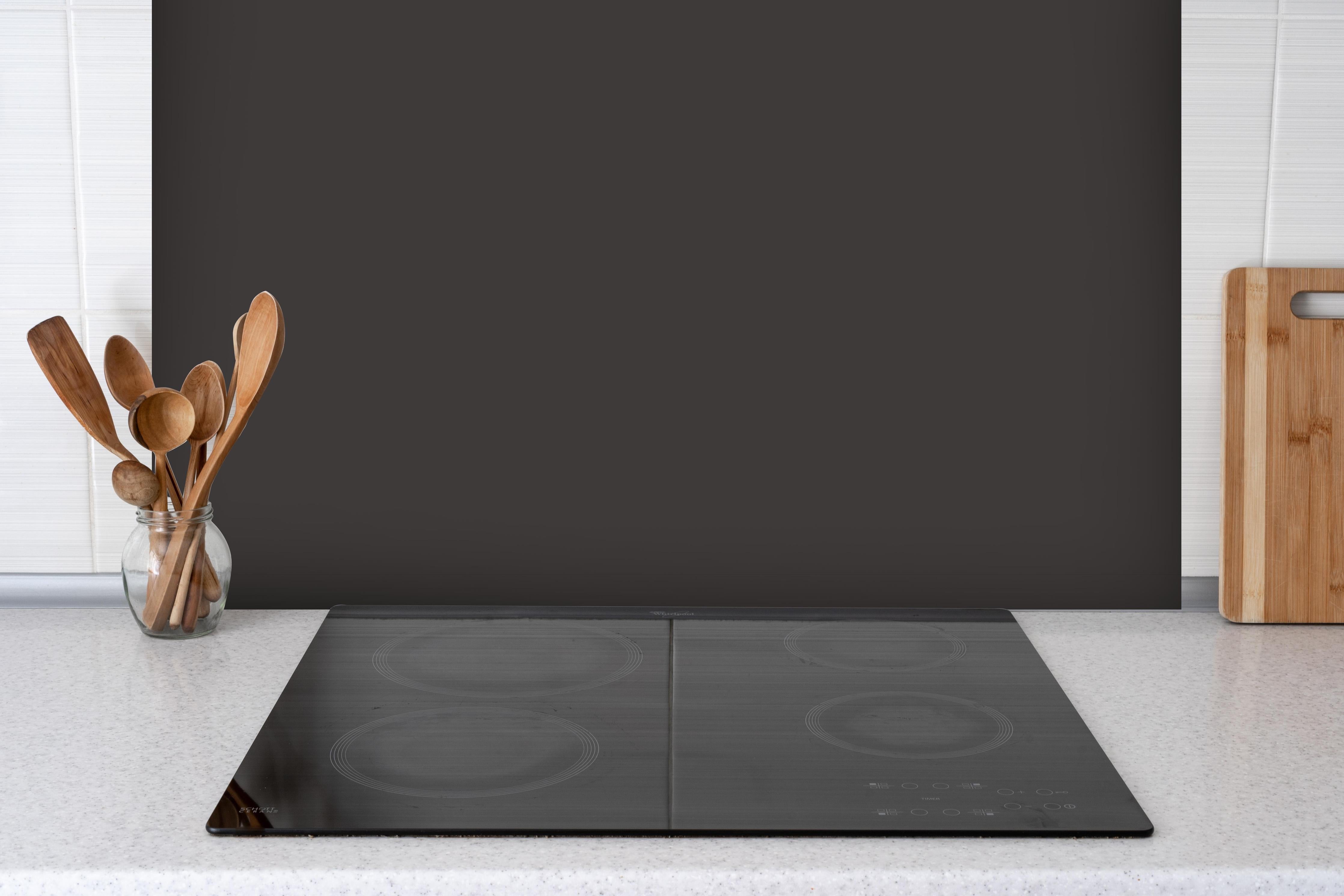 Spritzschutz - RAL 8019 (Graubraun) hinter einem Cerankochfeld zwischen Holz-Kochutensilien