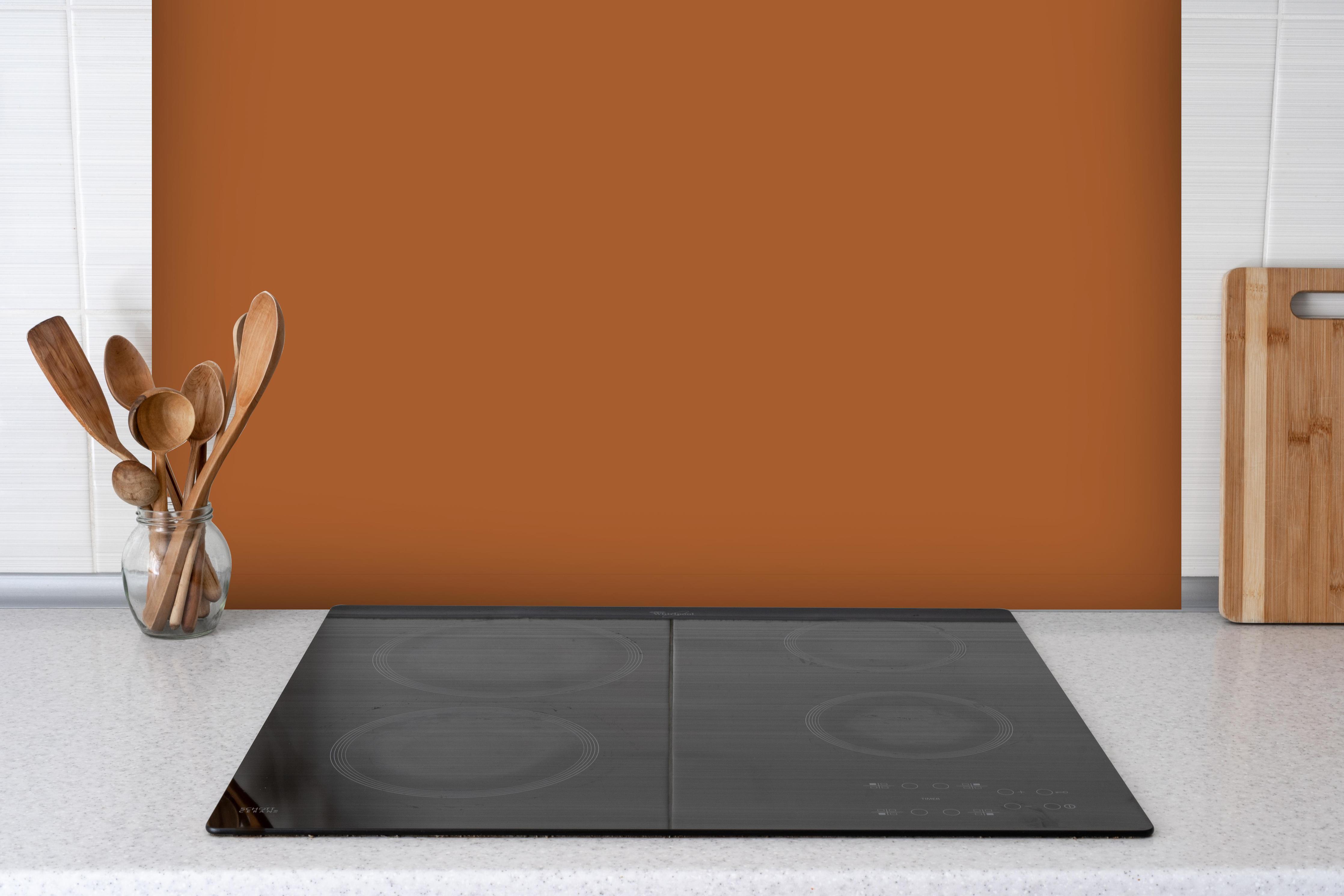 Spritzschutz - RAL 8023 (Orangebraun) hinter einem Cerankochfeld zwischen Holz-Kochutensilien