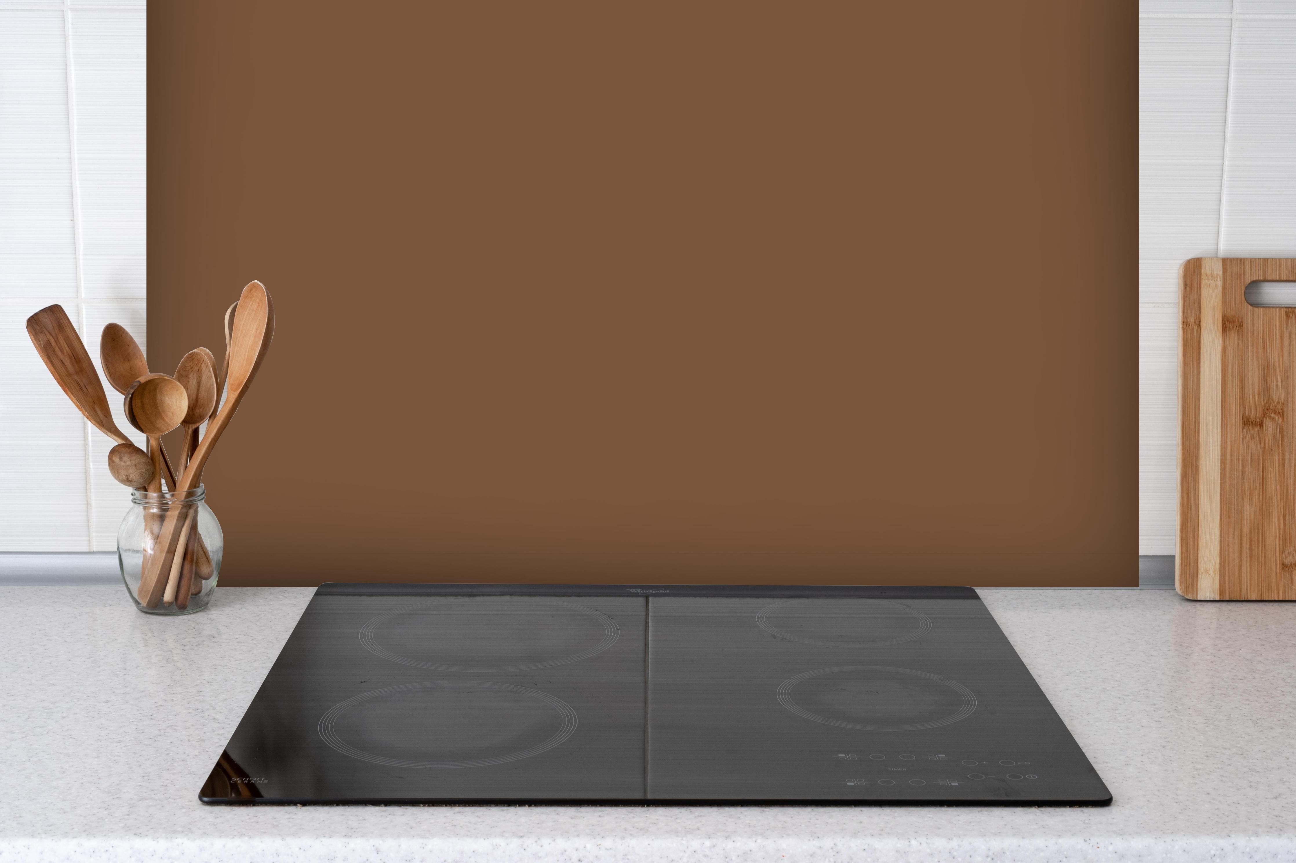 Spritzschutz - RAL 8024 (Beigebraun) hinter einem Cerankochfeld zwischen Holz-Kochutensilien