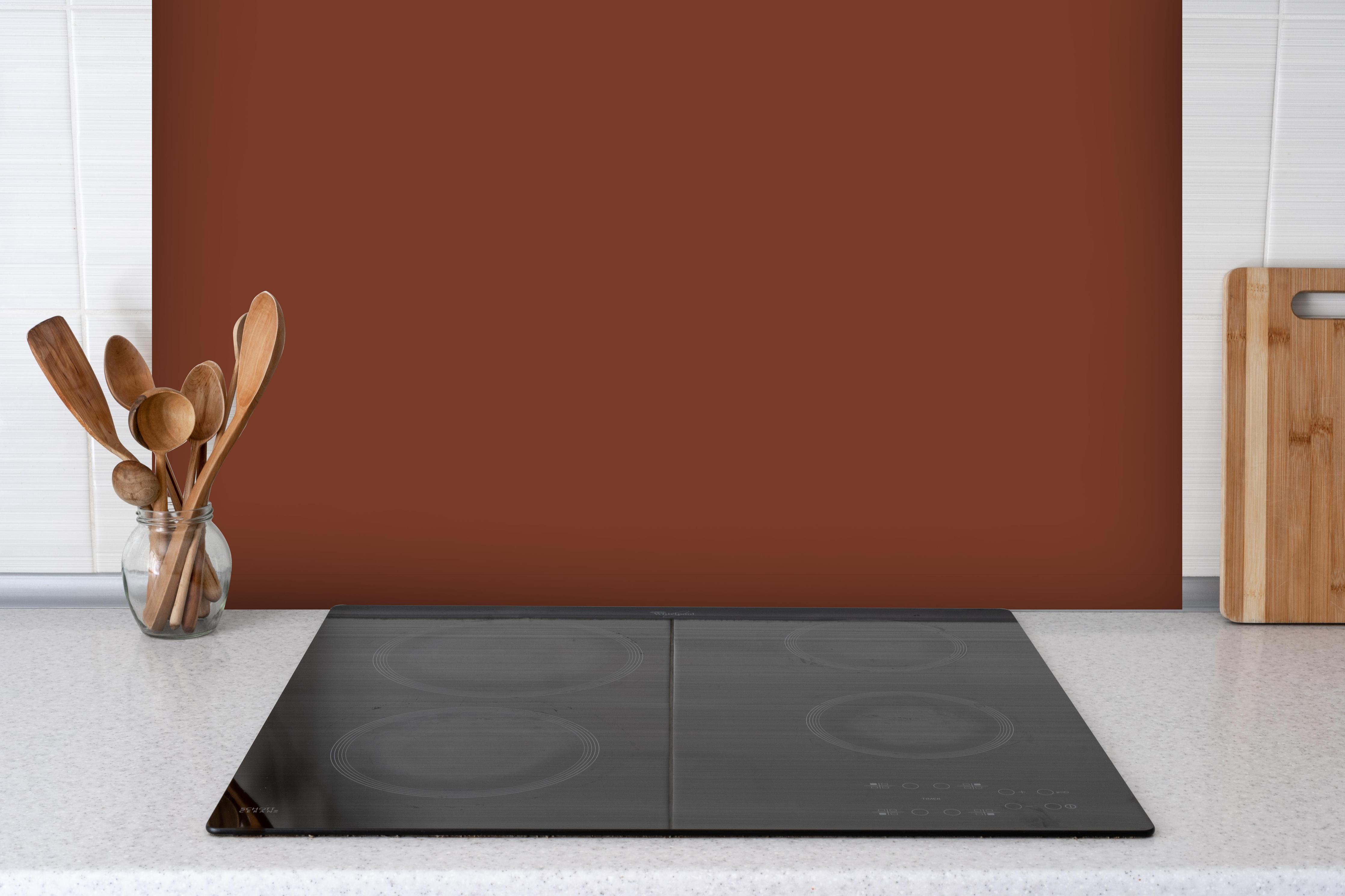 Spritzschutz - RAL 8029 (Perlkupfer) hinter einem Cerankochfeld zwischen Holz-Kochutensilien