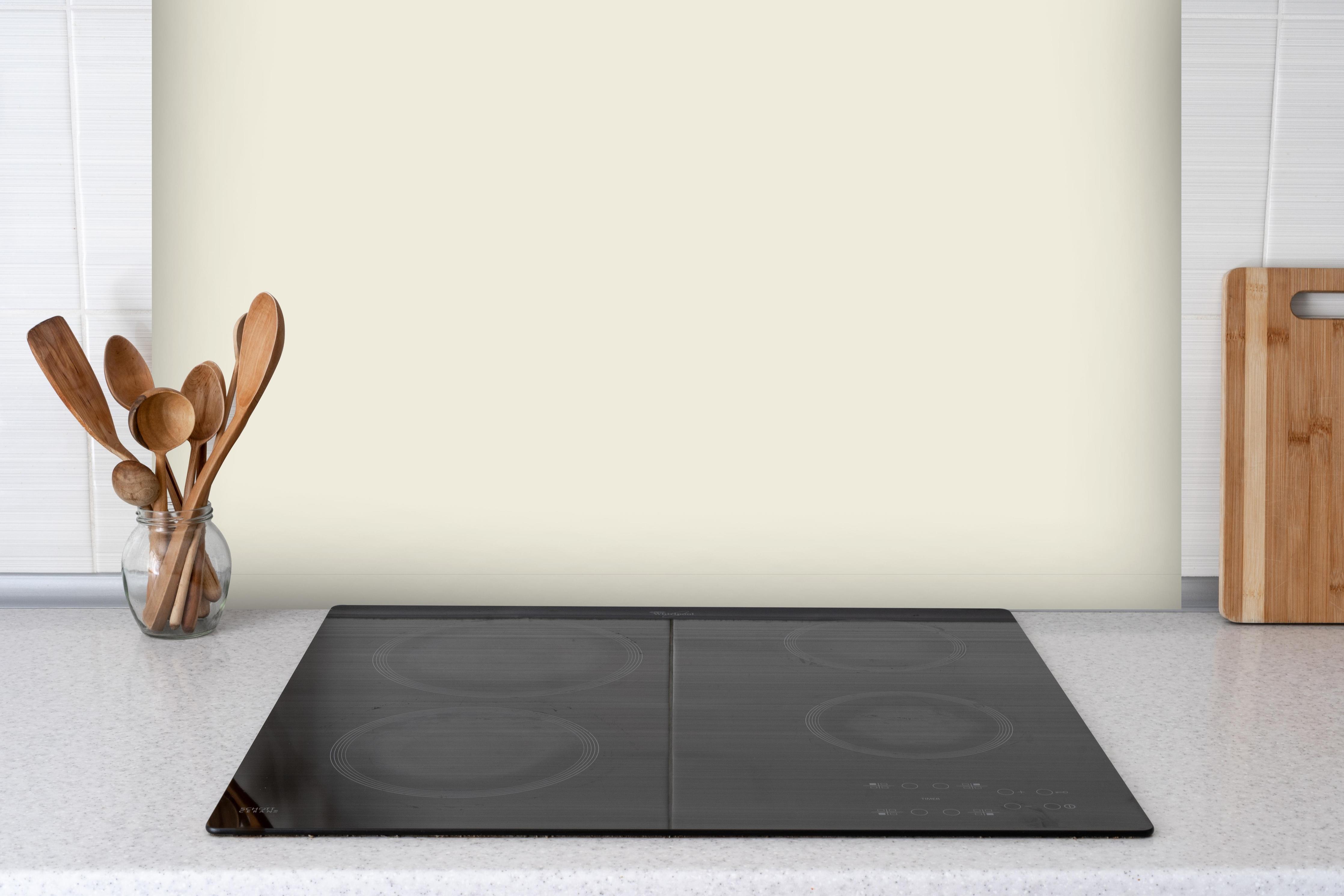 Spritzschutz - RAL 9001 (Creme) hinter einem Cerankochfeld zwischen Holz-Kochutensilien