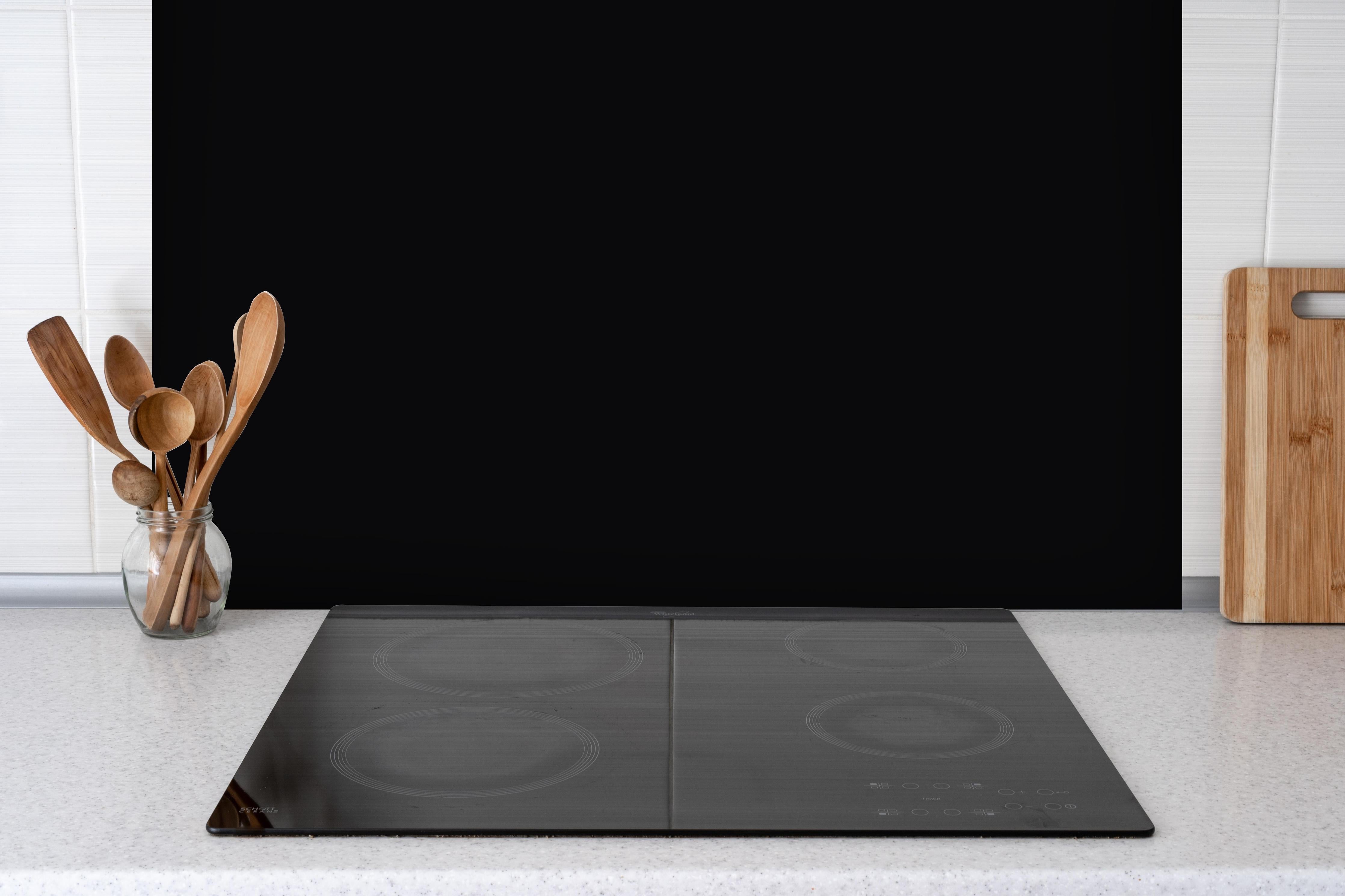 Spritzschutz - RAL 9005 (Tiefschwarz) hinter einem Cerankochfeld zwischen Holz-Kochutensilien