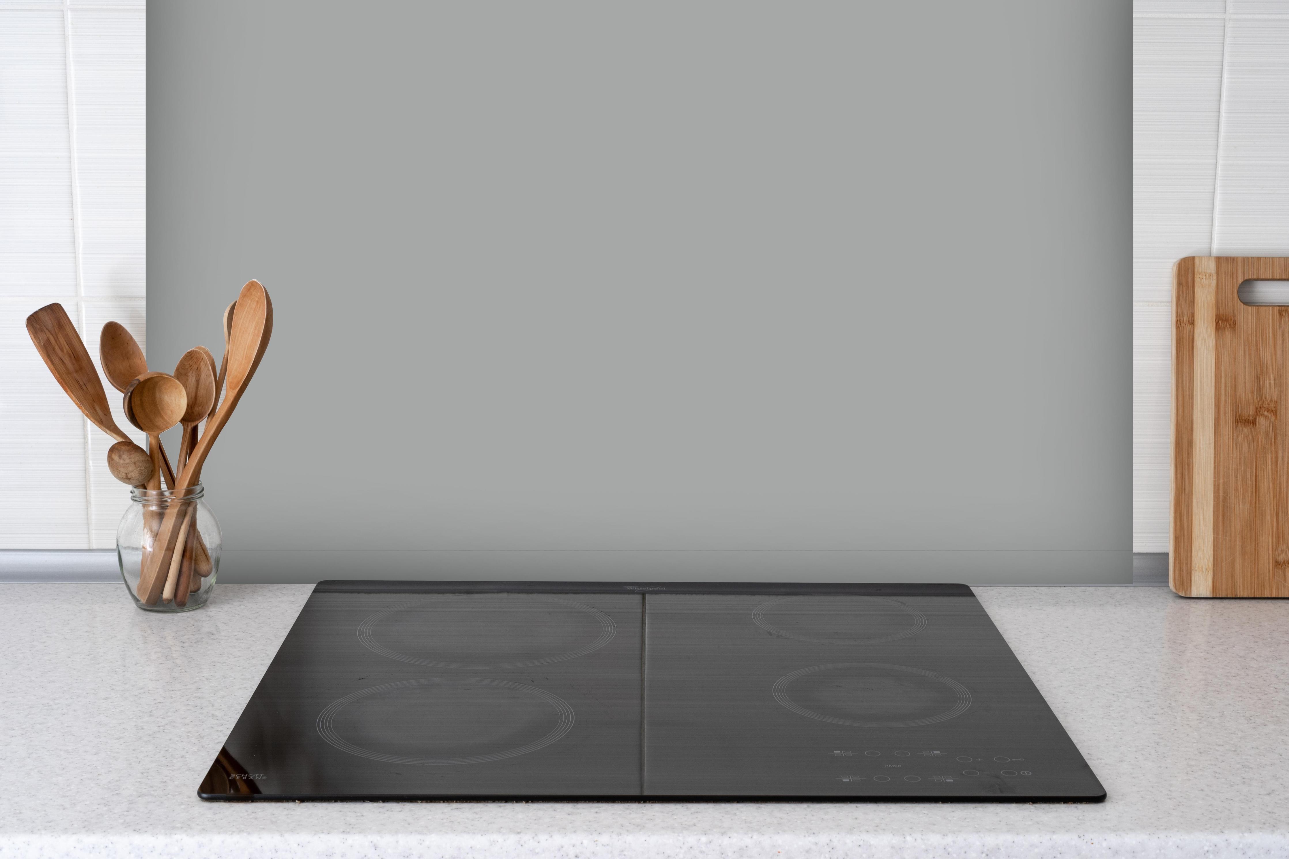 Spritzschutz - RAL 9006 (Weißaluminium) hinter einem Cerankochfeld zwischen Holz-Kochutensilien