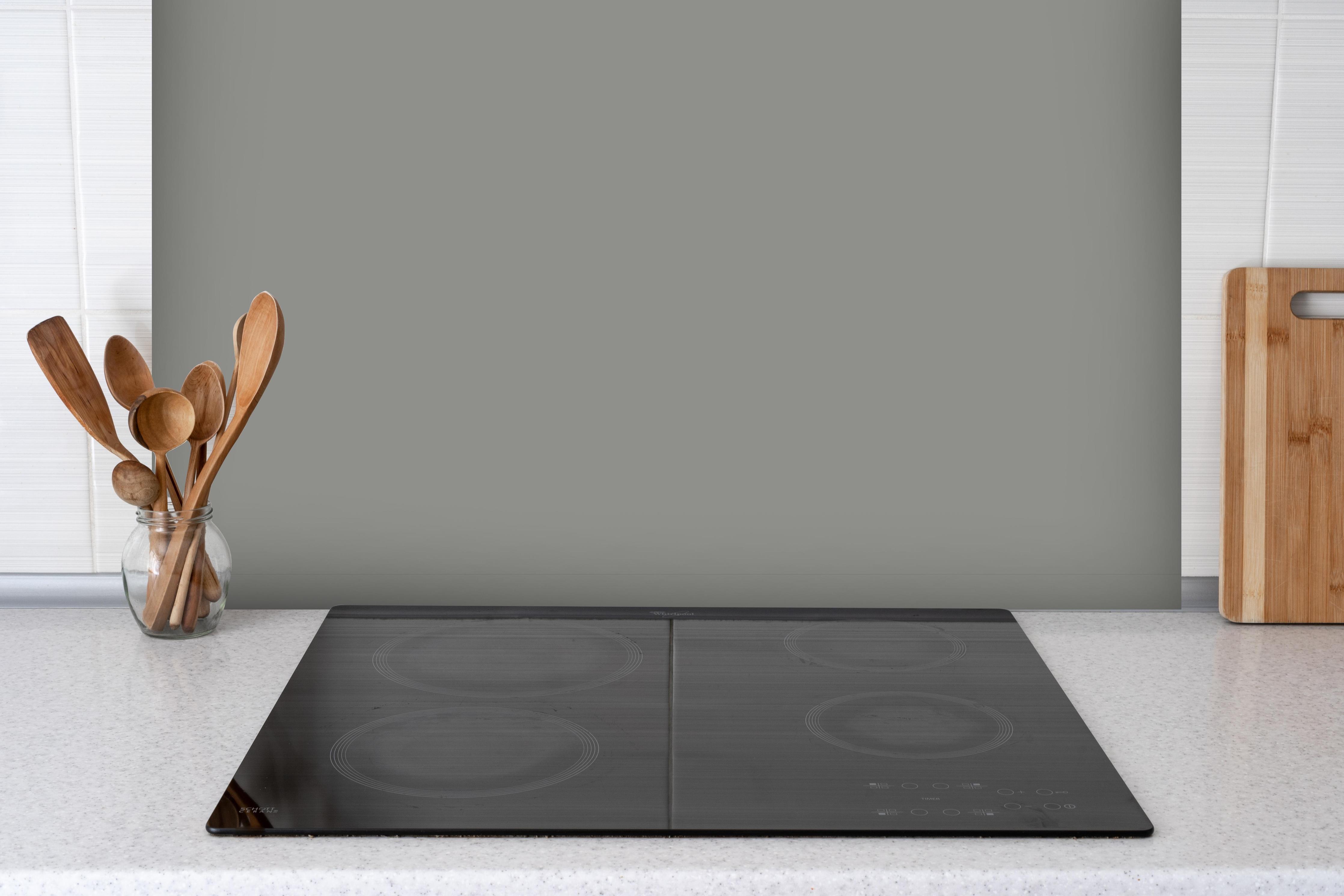 Spritzschutz - RAL 9007 (Graualuminium) hinter einem Cerankochfeld zwischen Holz-Kochutensilien