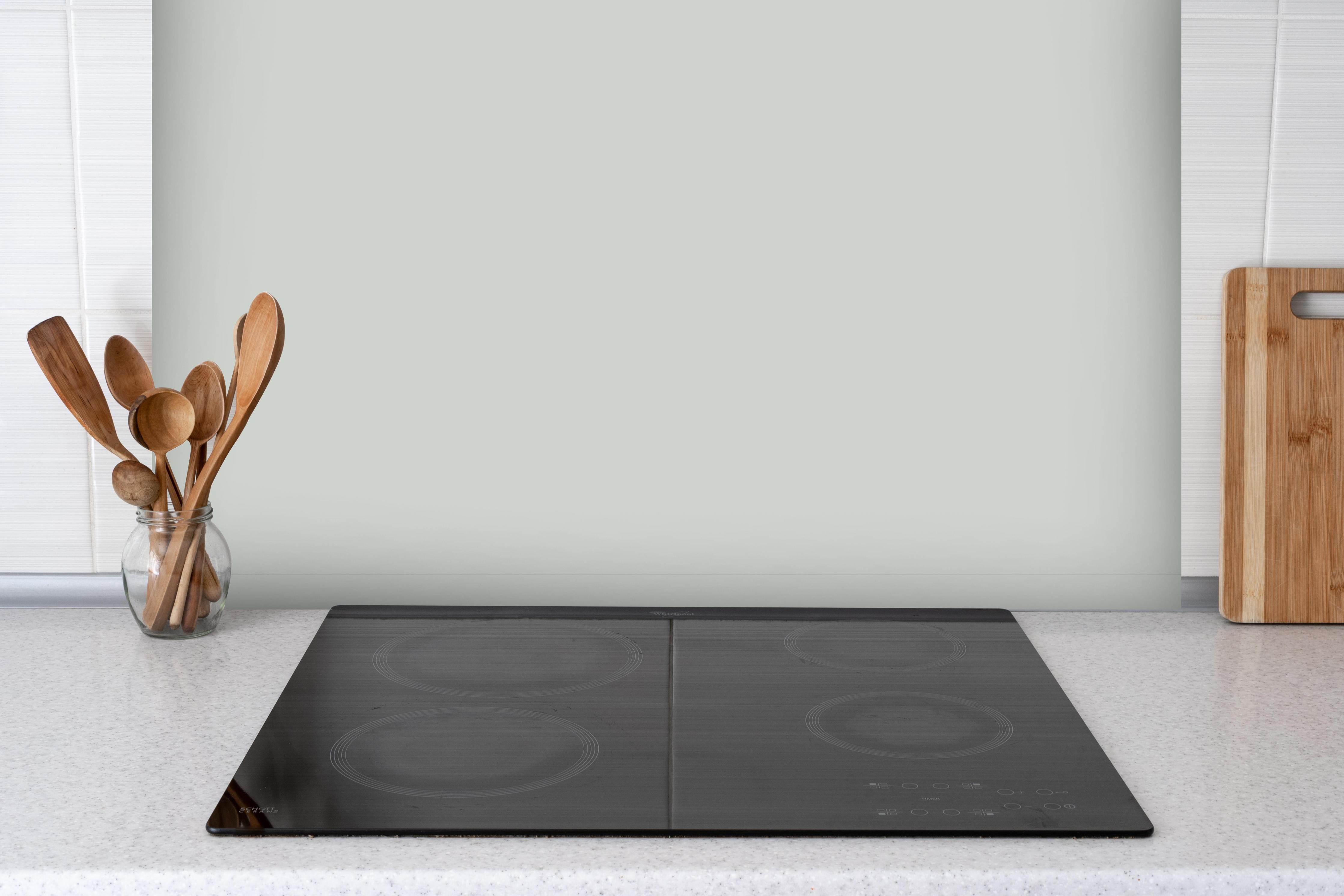 Spritzschutz - RAL 9018 (Papyrusweiß) hinter einem Cerankochfeld zwischen Holz-Kochutensilien