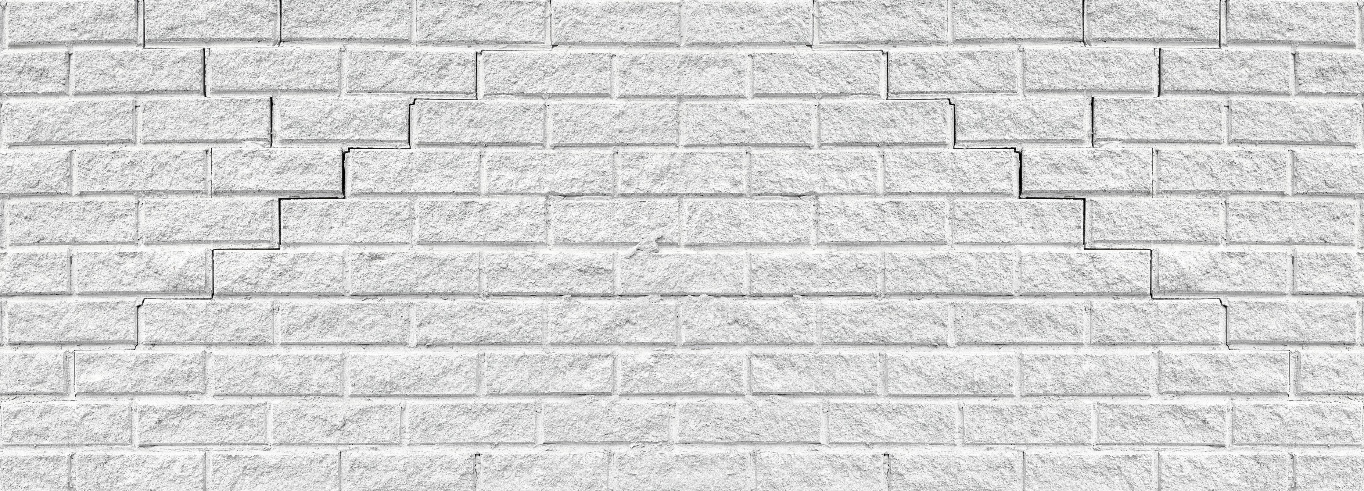 Spritzschutz-Rissige weiße Ziegelwand