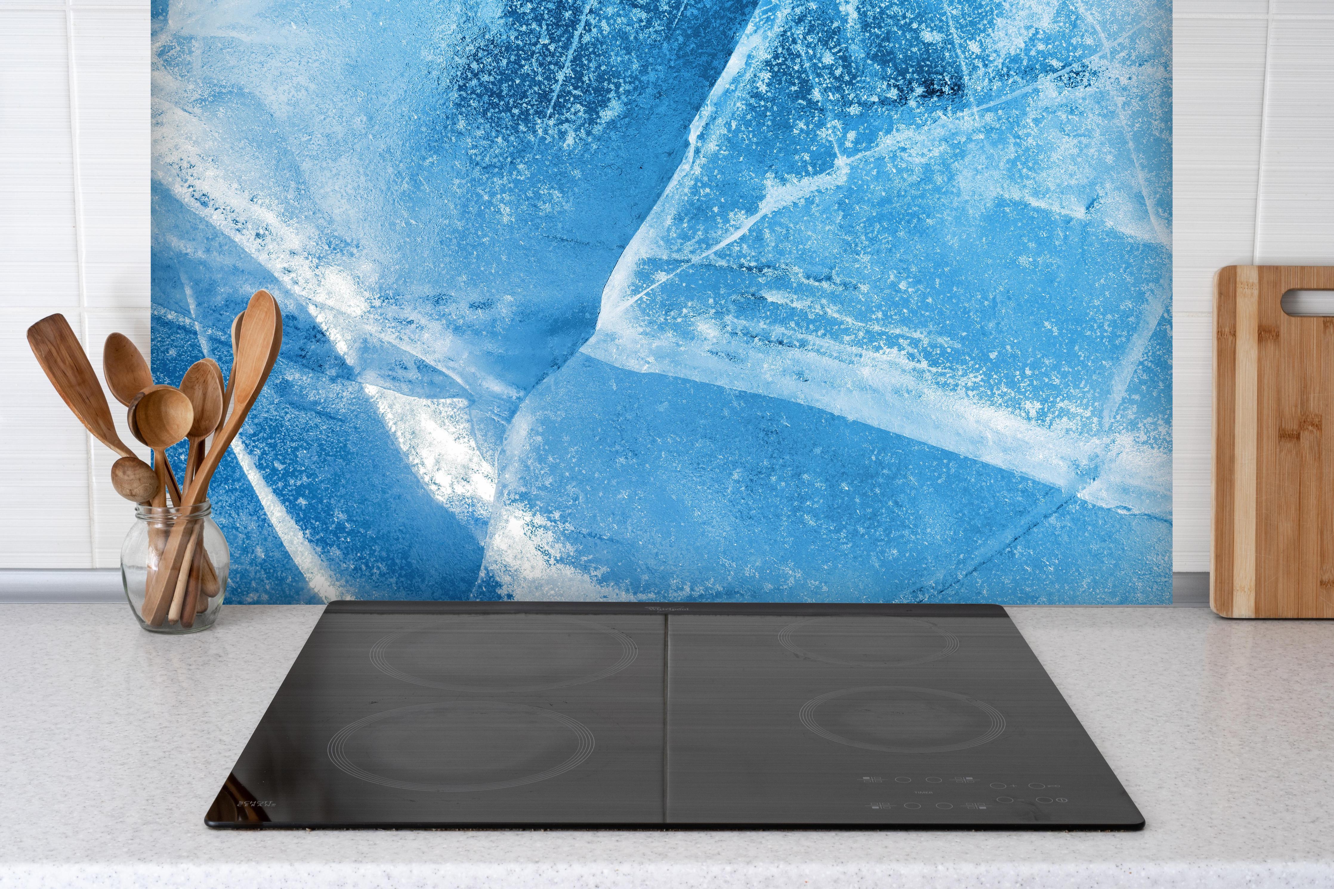 Spritzschutz - Rissiger Eisblock hinter einem Cerankochfeld zwischen Holz-Kochutensilien
