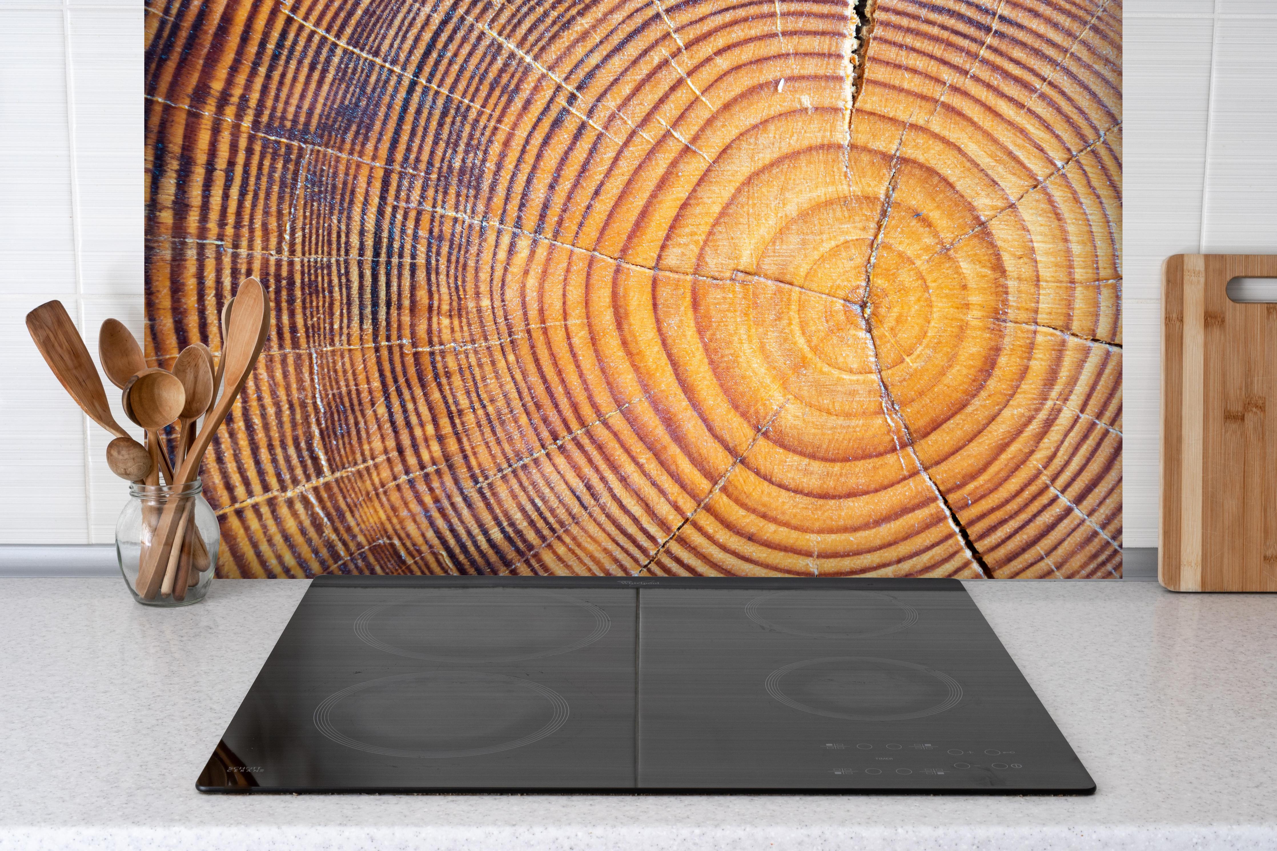 Spritzschutz - Rissiger Holzstumpf hinter einem Cerankochfeld zwischen Holz-Kochutensilien