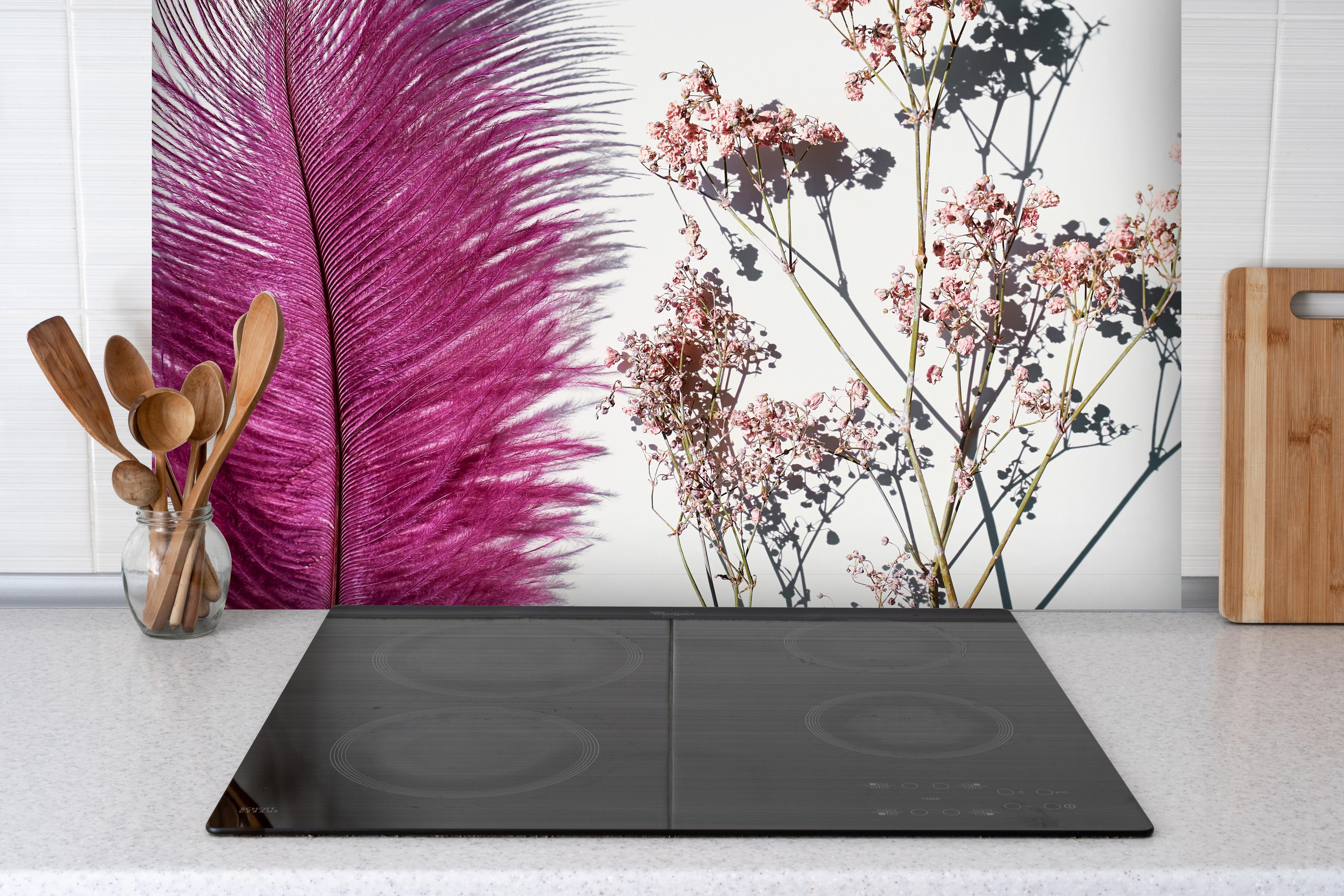 Spritzschutz - Rosa Feder und Trockenblumen hinter einem Cerankochfeld zwischen Holz-Kochutensilien