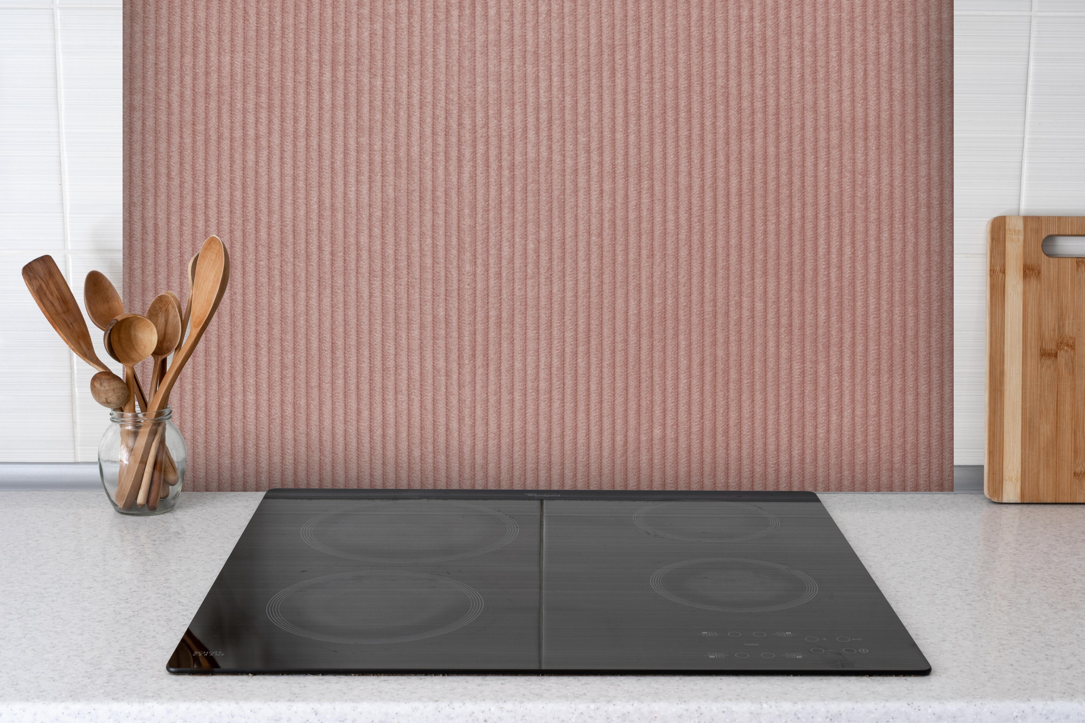 Spritzschutz - Rotbraunes Kord Textil hinter einem Cerankochfeld zwischen Holz-Kochutensilien