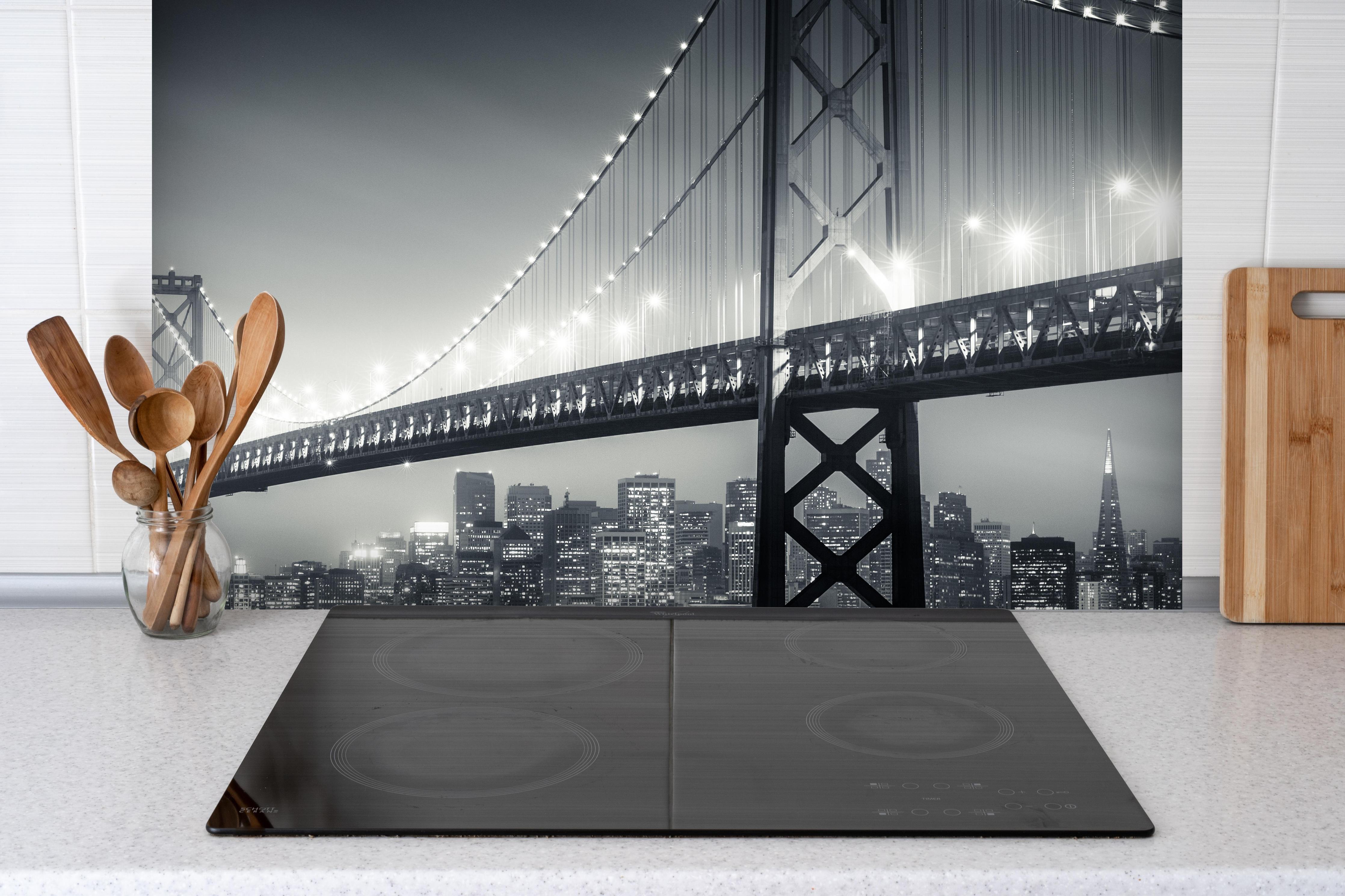 Spritzschutz - San Francisco Bay Bridge bei Nacht hinter einem Cerankochfeld zwischen Holz-Kochutensilien