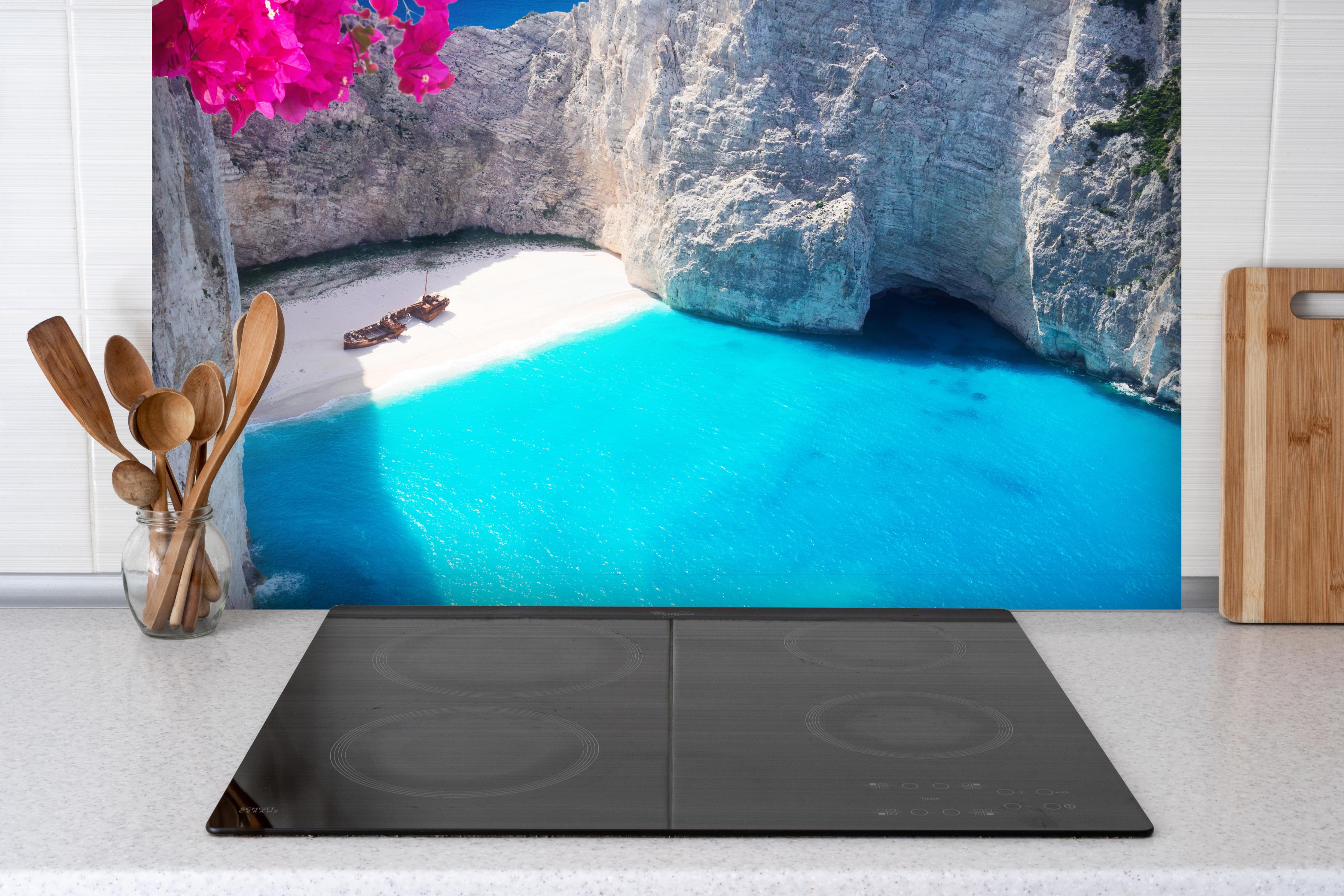 Spritzschutz - Schöne Landschaft der Insel Zakinthos hinter einem Cerankochfeld zwischen Holz-Kochutensilien