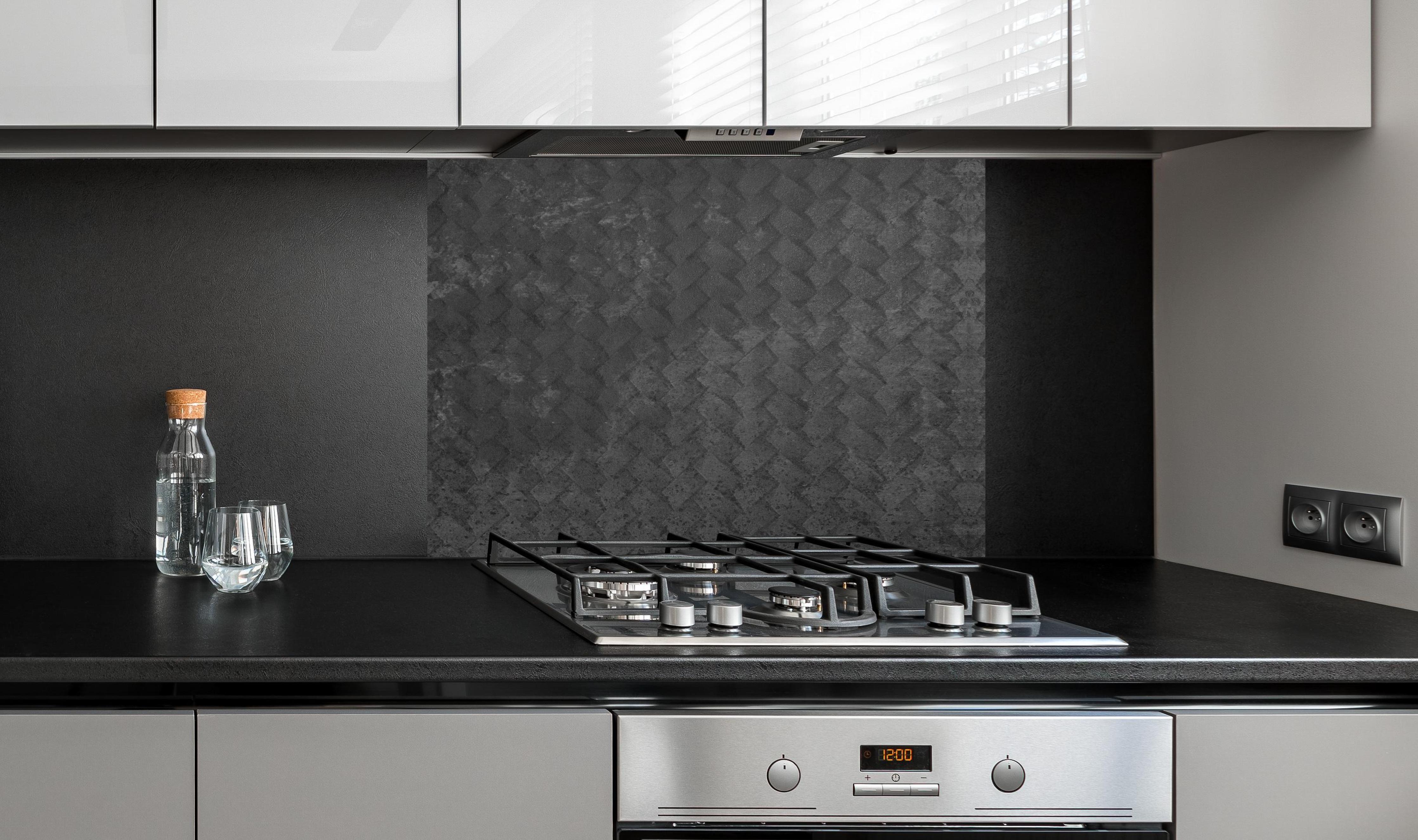 Spritzschutz - Schwarze geometrisches Betonwand an edler Anthrazit-Wand hinter silbernem Gasherd