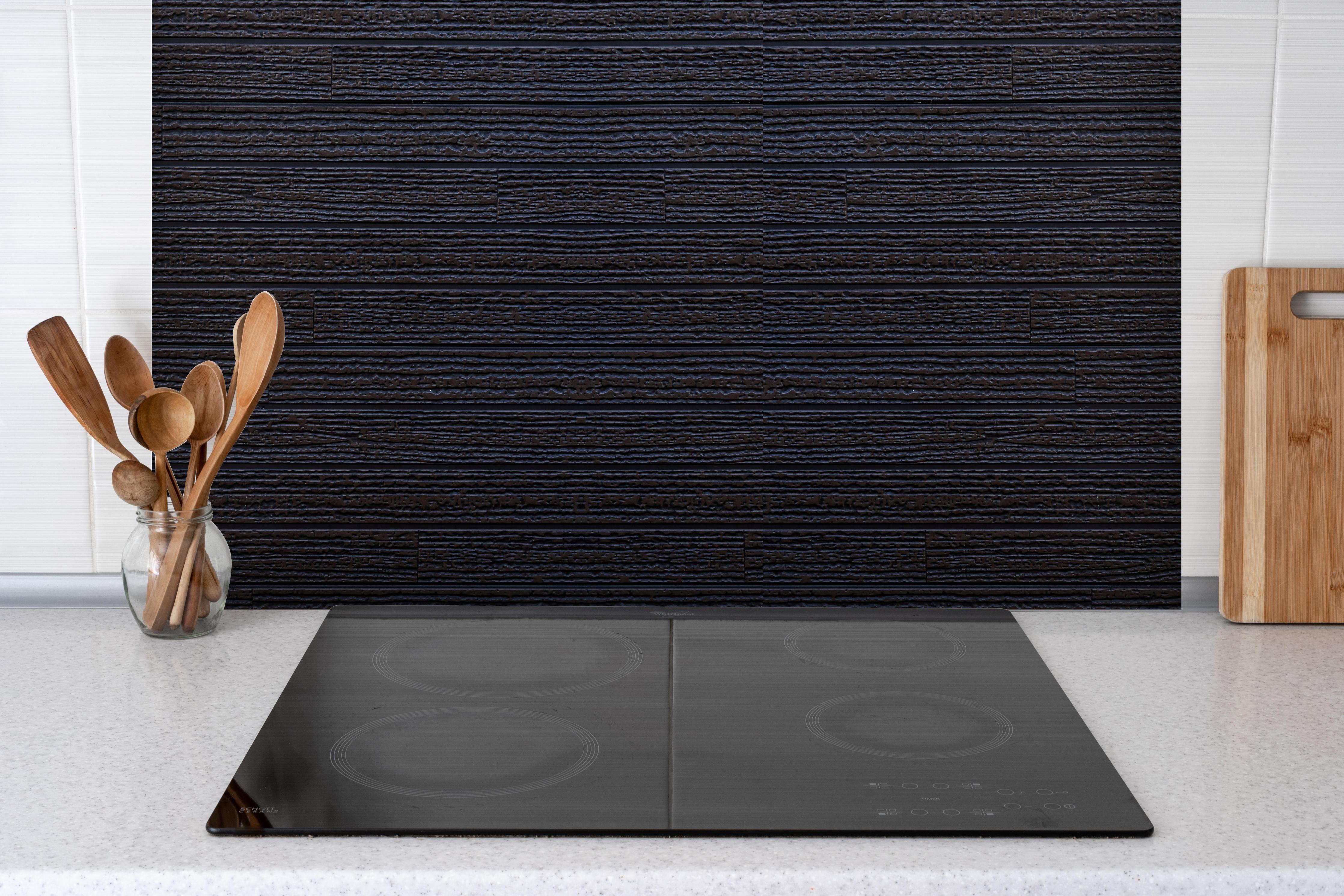 Spritzschutz - Schwarzes Holz - Vintage hinter einem Cerankochfeld zwischen Holz-Kochutensilien