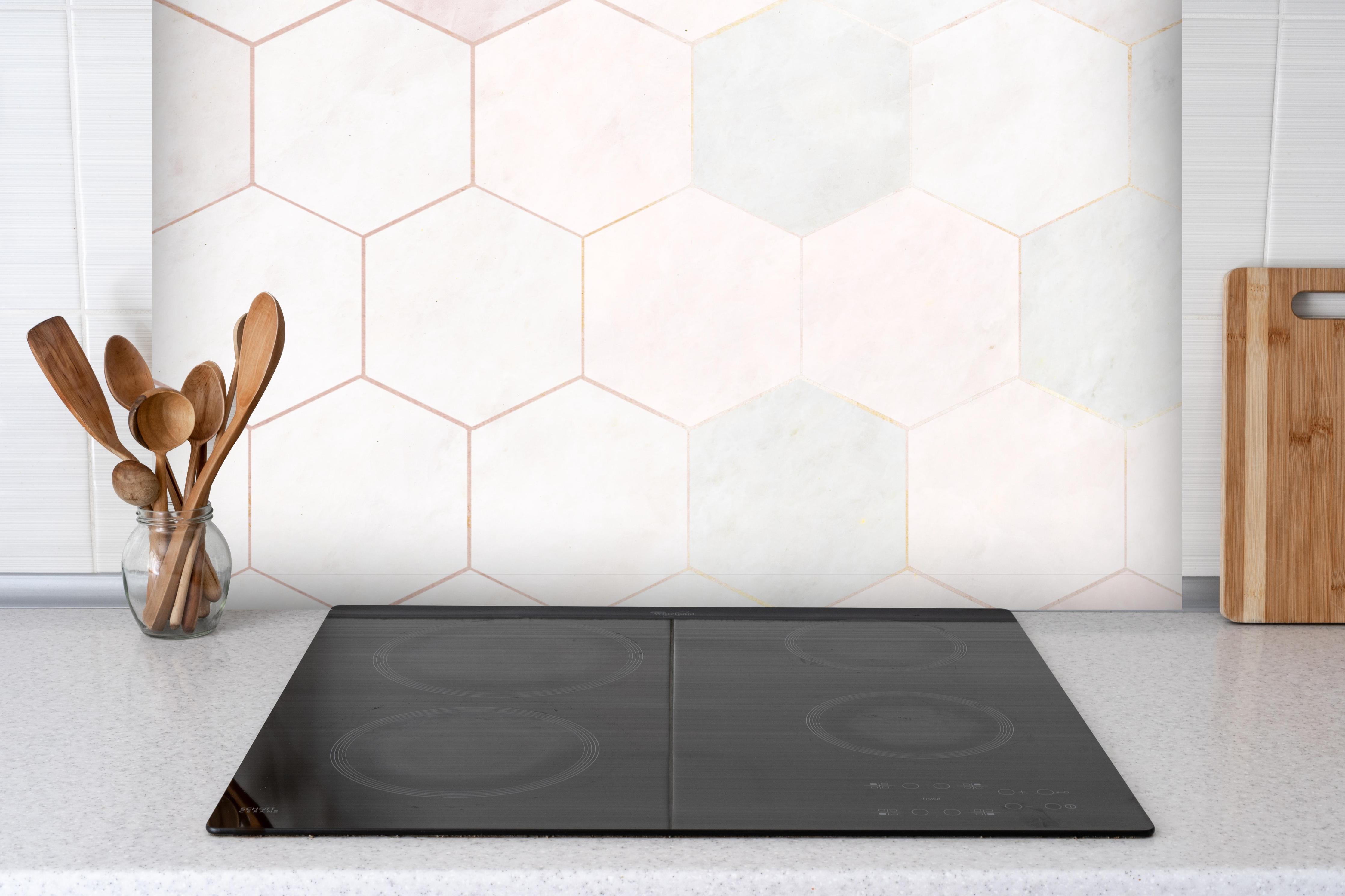 Spritzschutz - Sechseck rosa Marmor Muster hinter einem Cerankochfeld zwischen Holz-Kochutensilien