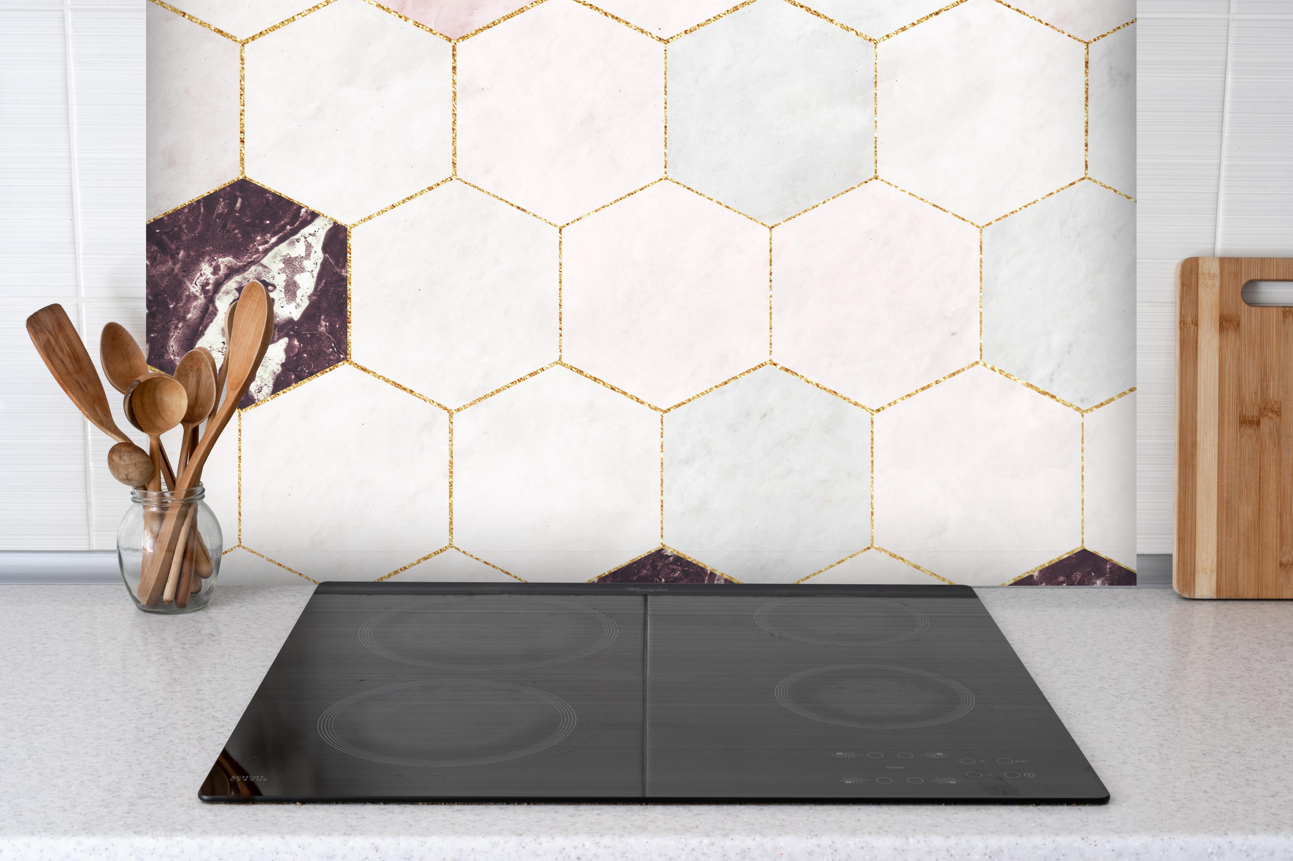 Spritzschutz - Sechseckige rosafarbiger Marmor mit Goldumrandung hinter einem Cerankochfeld zwischen Holz-Kochutensilien