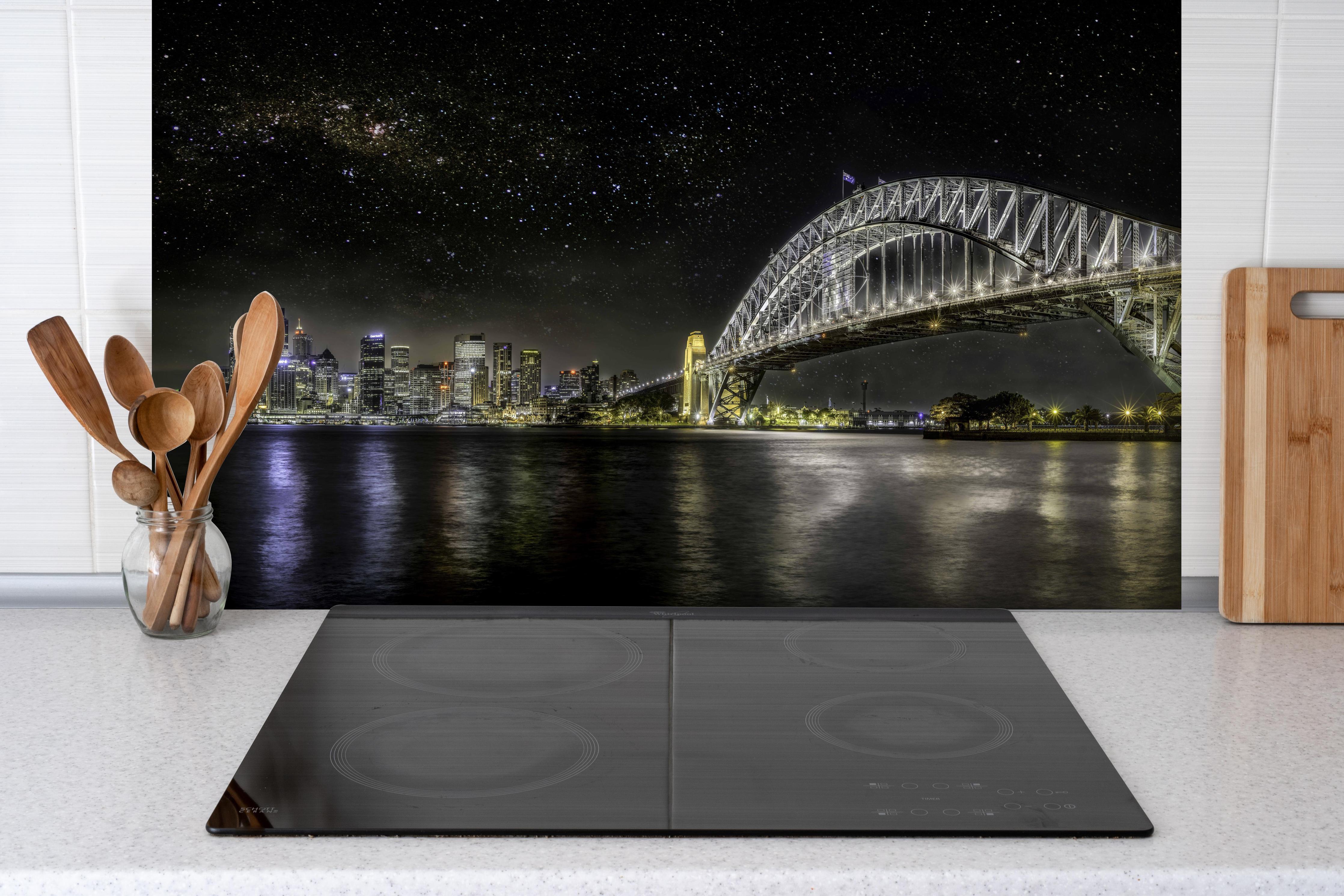 Spritzschutz - Skyline - Sydney hinter einem Cerankochfeld zwischen Holz-Kochutensilien