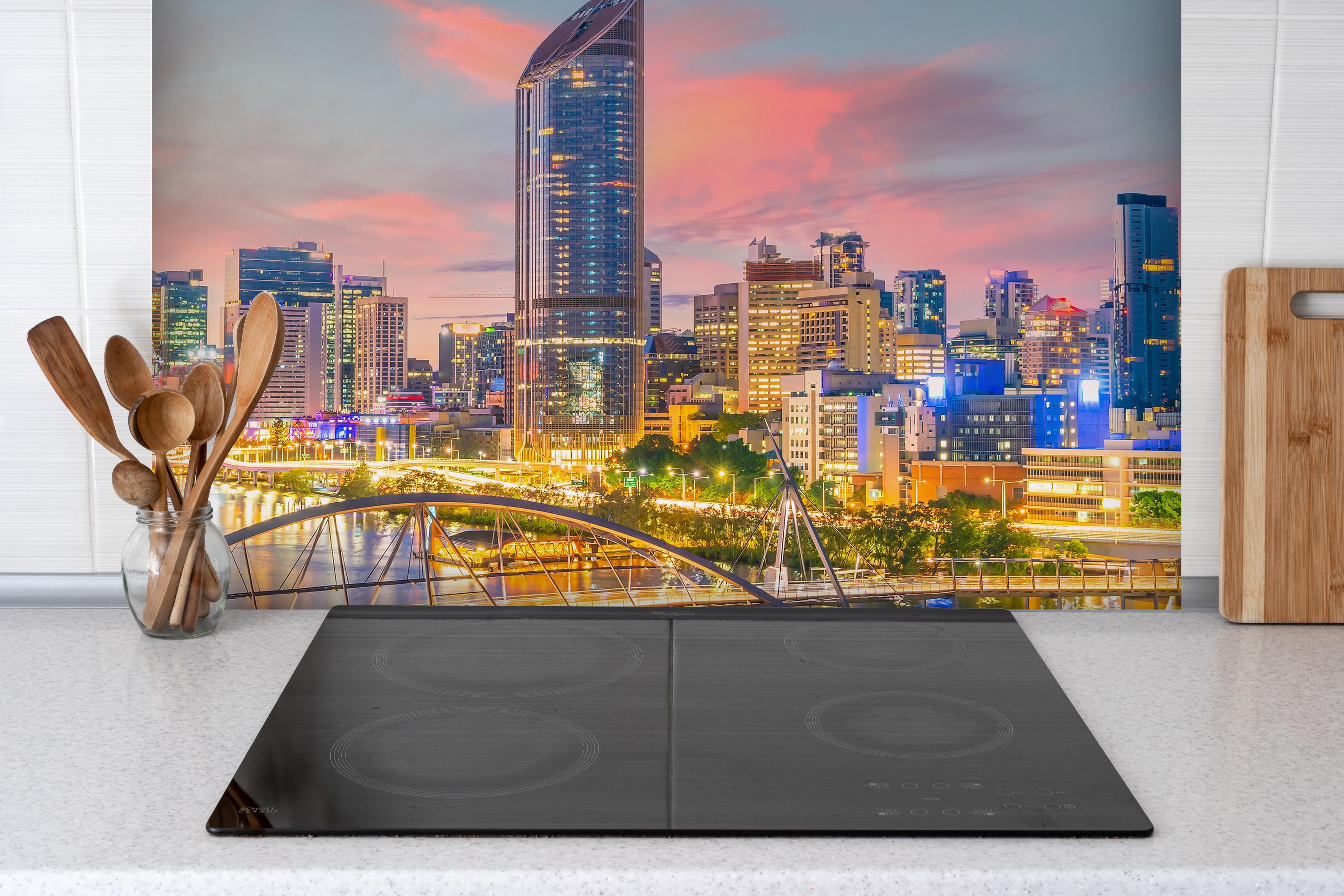 Spritzschutz - Skyline von Brisbane bei Sonnenuntergang hinter einem Cerankochfeld zwischen Holz-Kochutensilien
