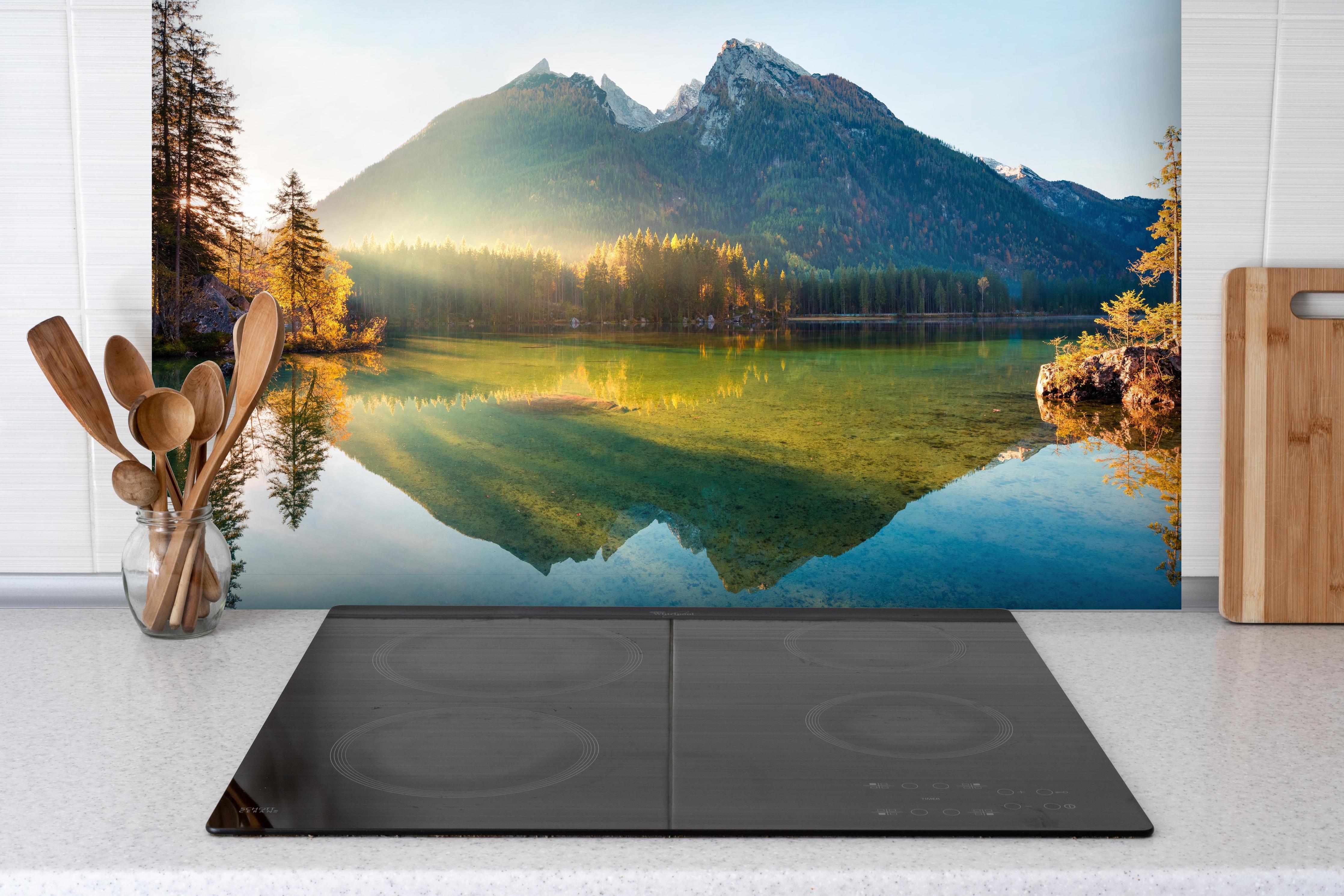 Spritzschutz - Sonnenaufgang am Hintersee hinter einem Cerankochfeld zwischen Holz-Kochutensilien