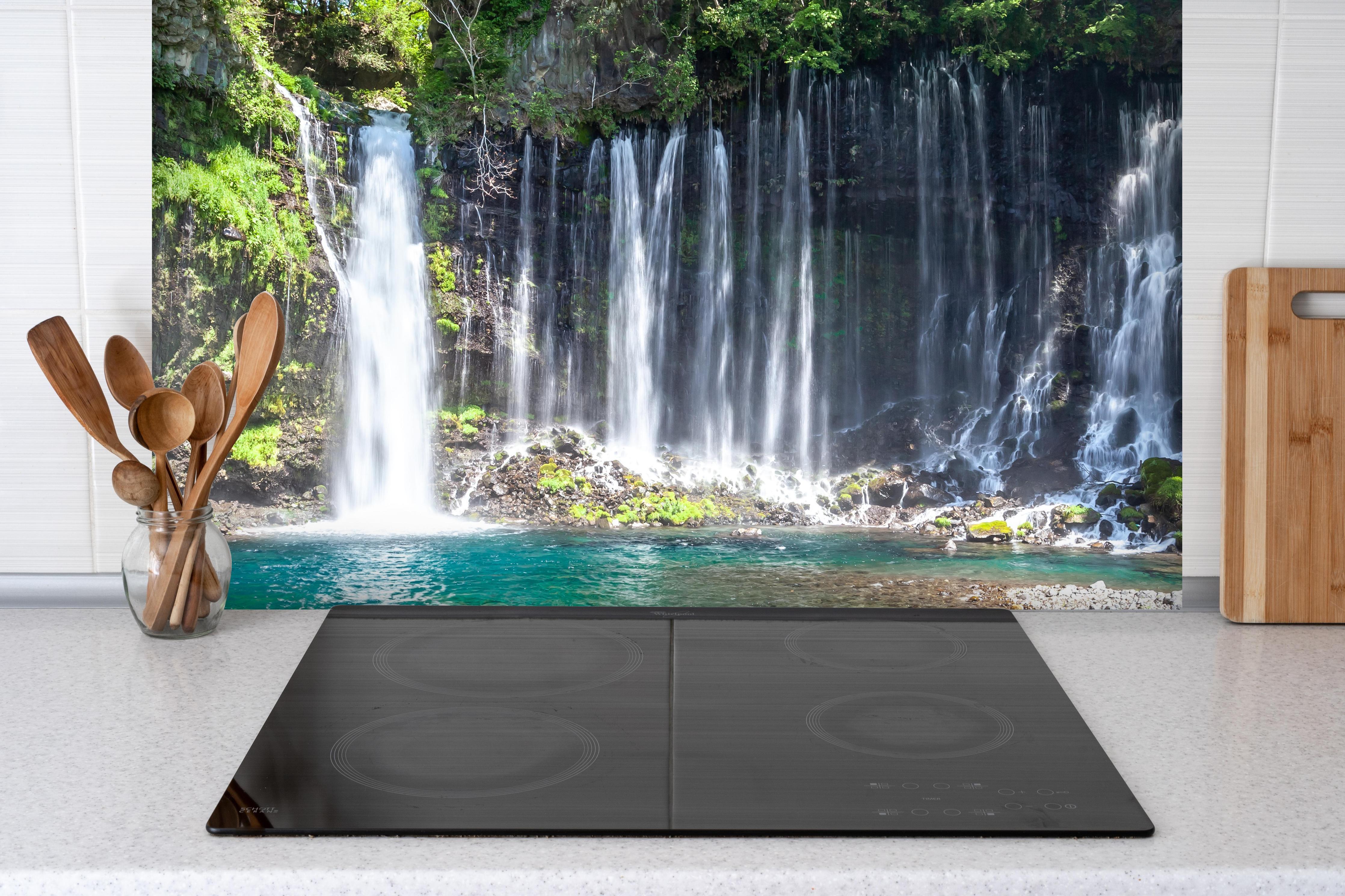 Spritzschutz - Sonniger Shiraito-Wasserfall hinter einem Cerankochfeld zwischen Holz-Kochutensilien