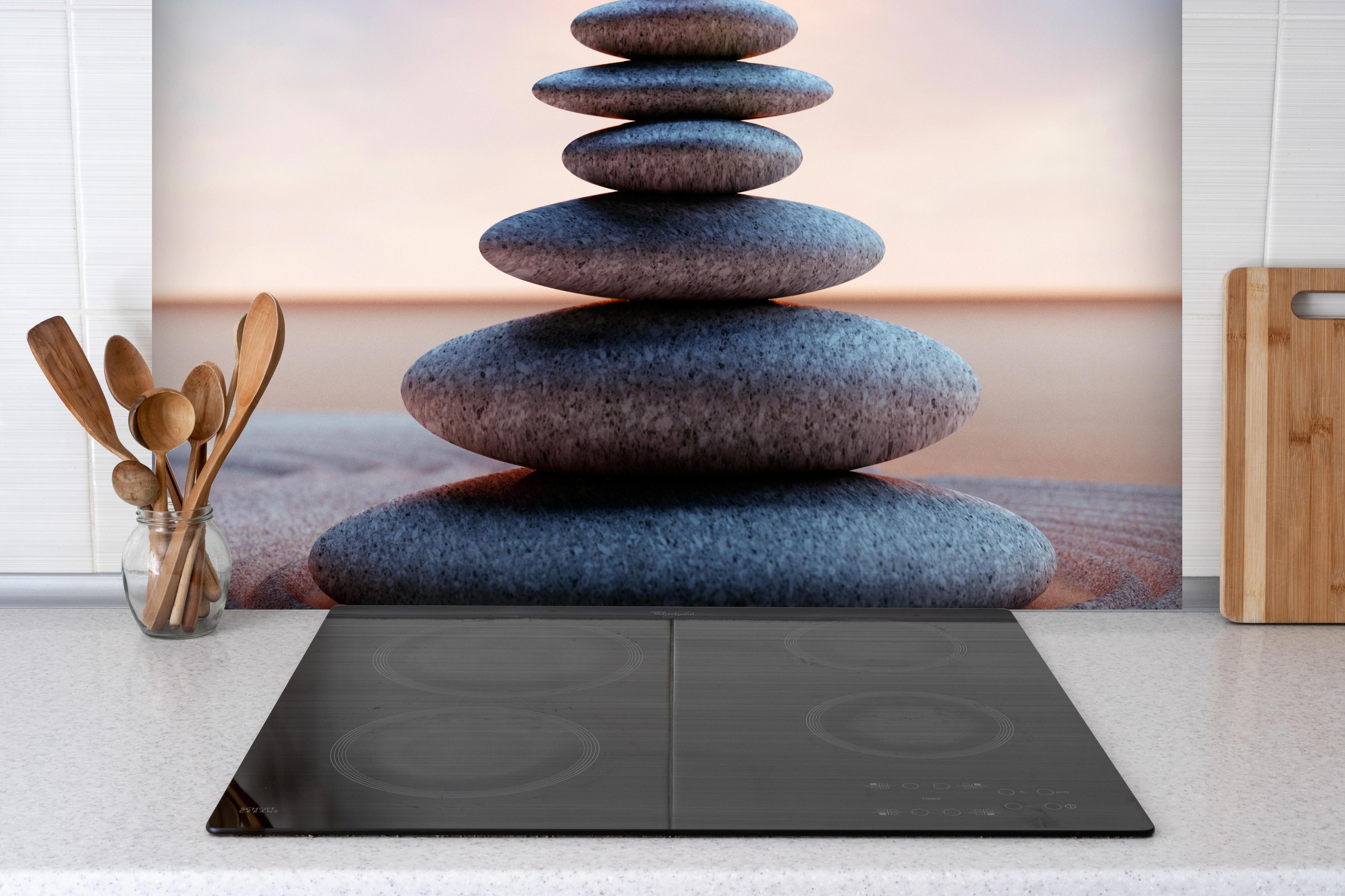 Spritzschutz - Spiritueller Steinturm mit Sonne hinter einem Cerankochfeld zwischen Holz-Kochutensilien