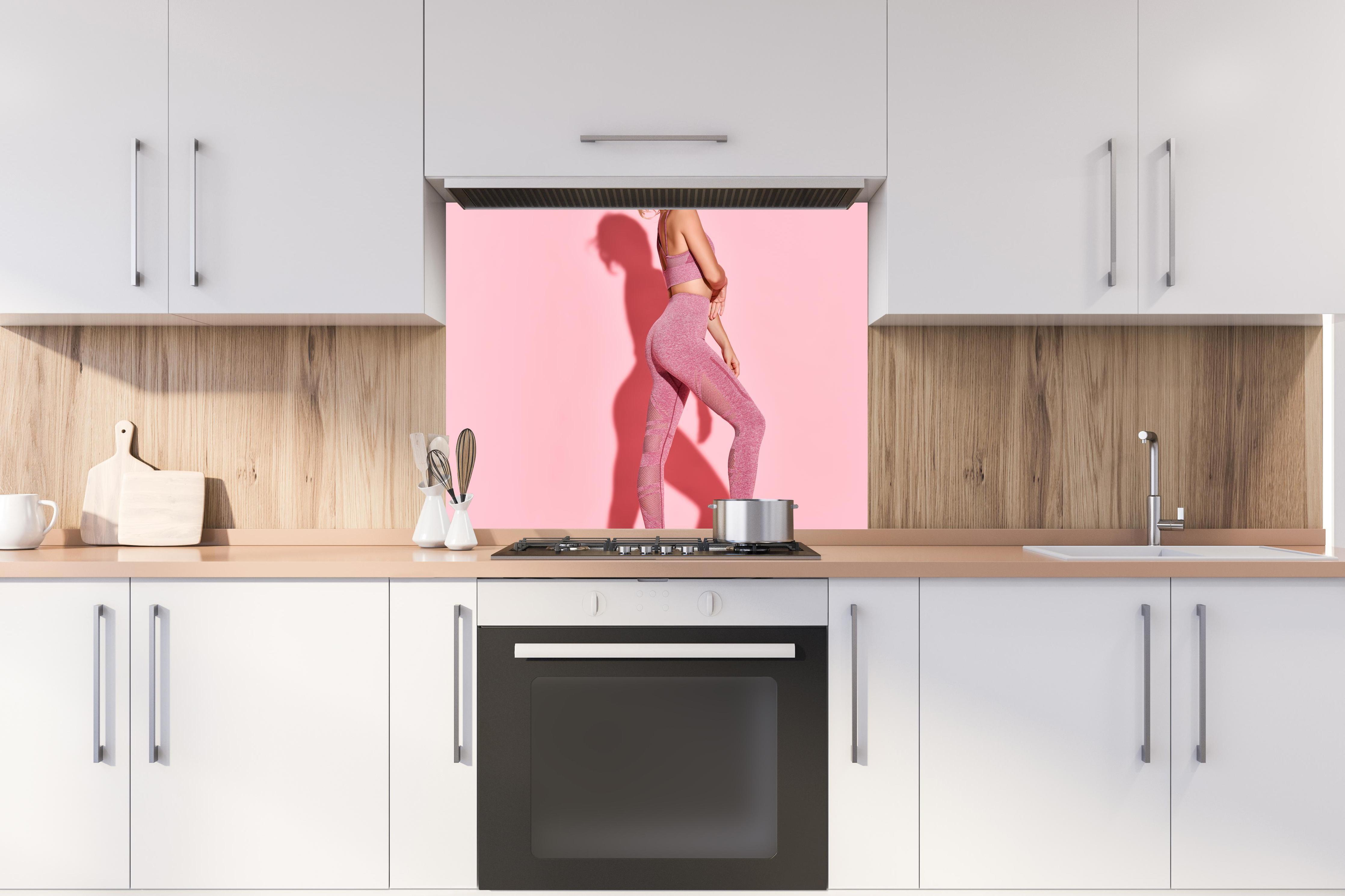 Spritzschutz - Sportliche Fitness-Frau hinter stilvollem Gasherd unter Dunstabzugshaube