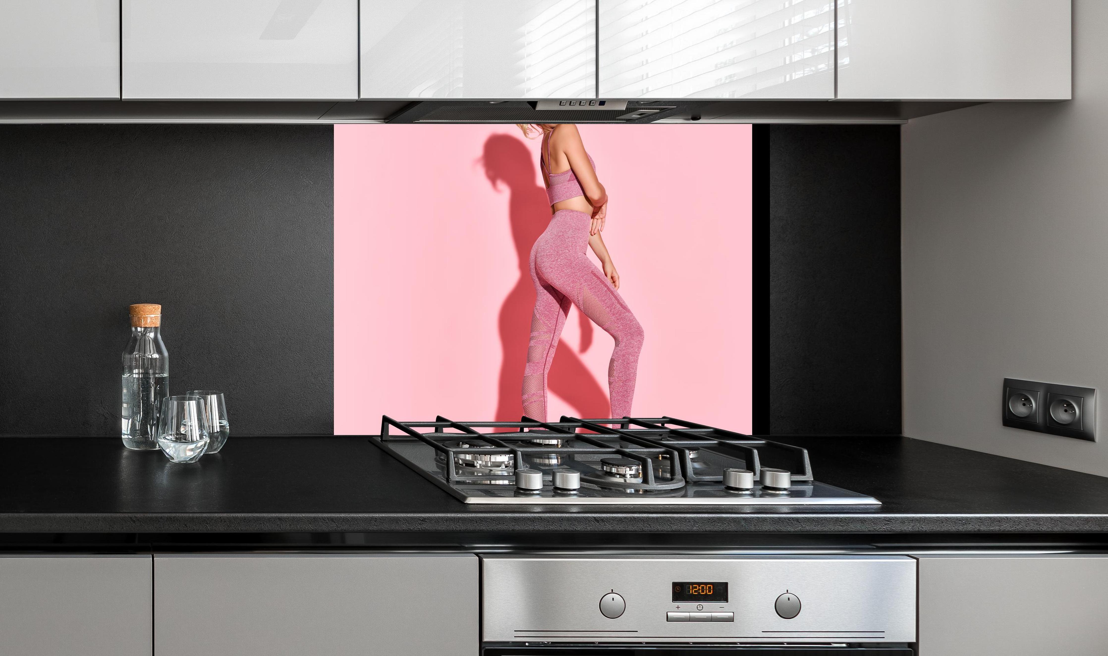 Spritzschutz - Sportliche Fitness-Frau an edler Anthrazit-Wand hinter silbernem Gasherd