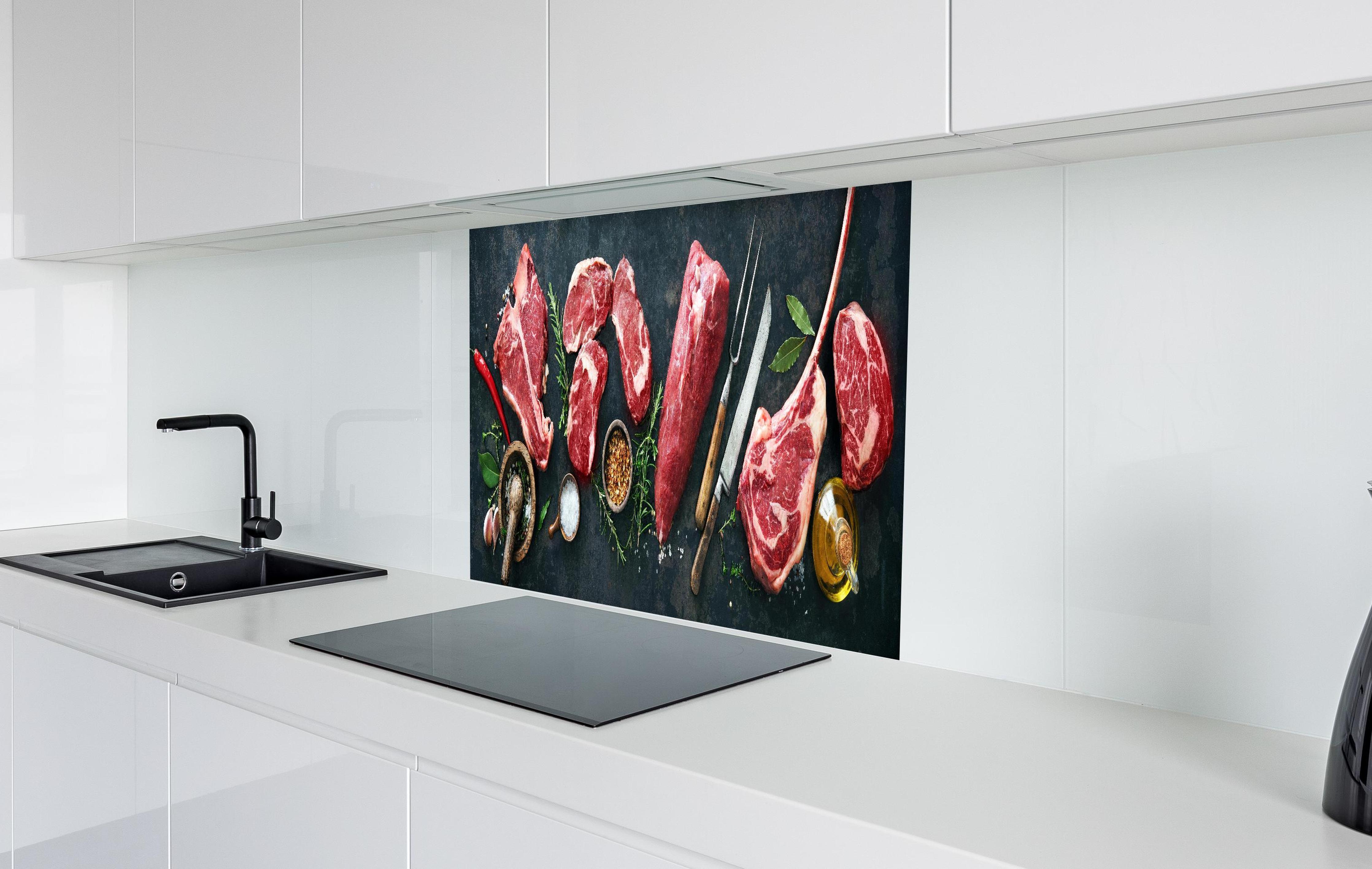 Spritzschutz - Steakvariationen auf Schieferplatte in weißer Hochglanz-Küche hinter einem Cerankochfeld