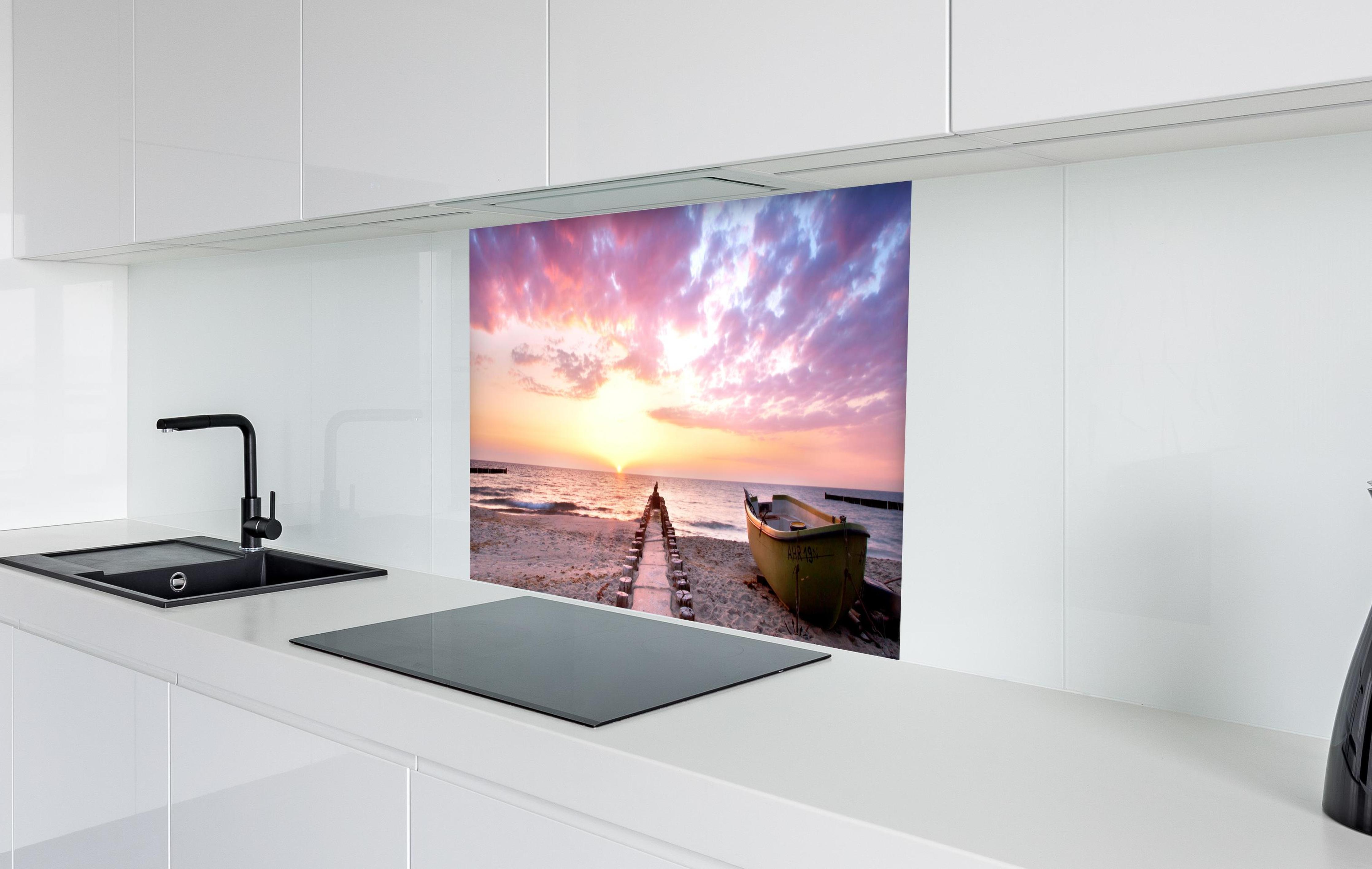Spritzschutz - Steg ins Meer bei Abendsonne in weißer Hochglanz-Küche hinter einem Cerankochfeld