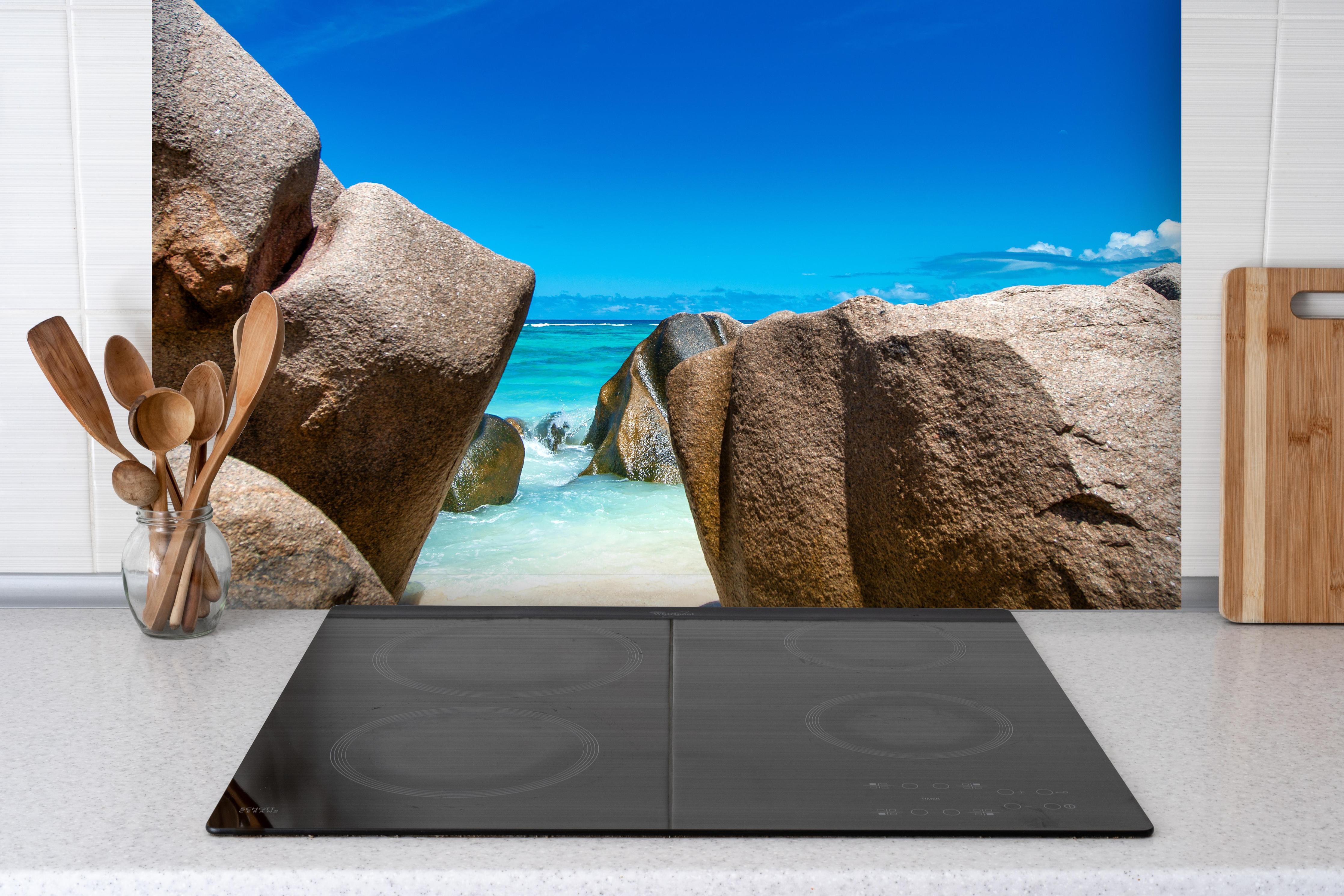 Spritzschutz - Stein-Panorama auf den Seychellen hinter einem Cerankochfeld zwischen Holz-Kochutensilien