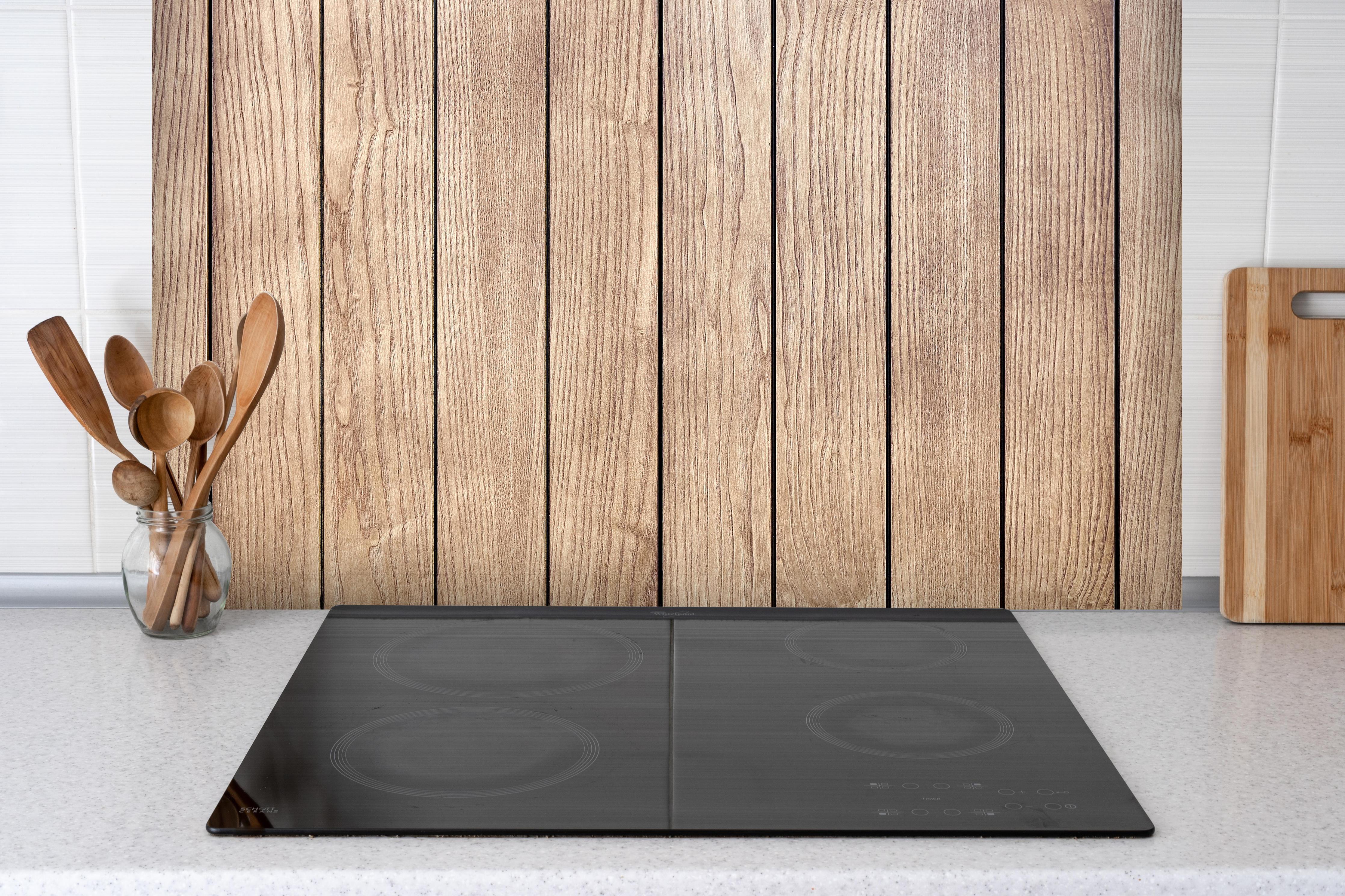 Spritzschutz - Stilvolle Eschenholzdielen hinter einem Cerankochfeld zwischen Holz-Kochutensilien