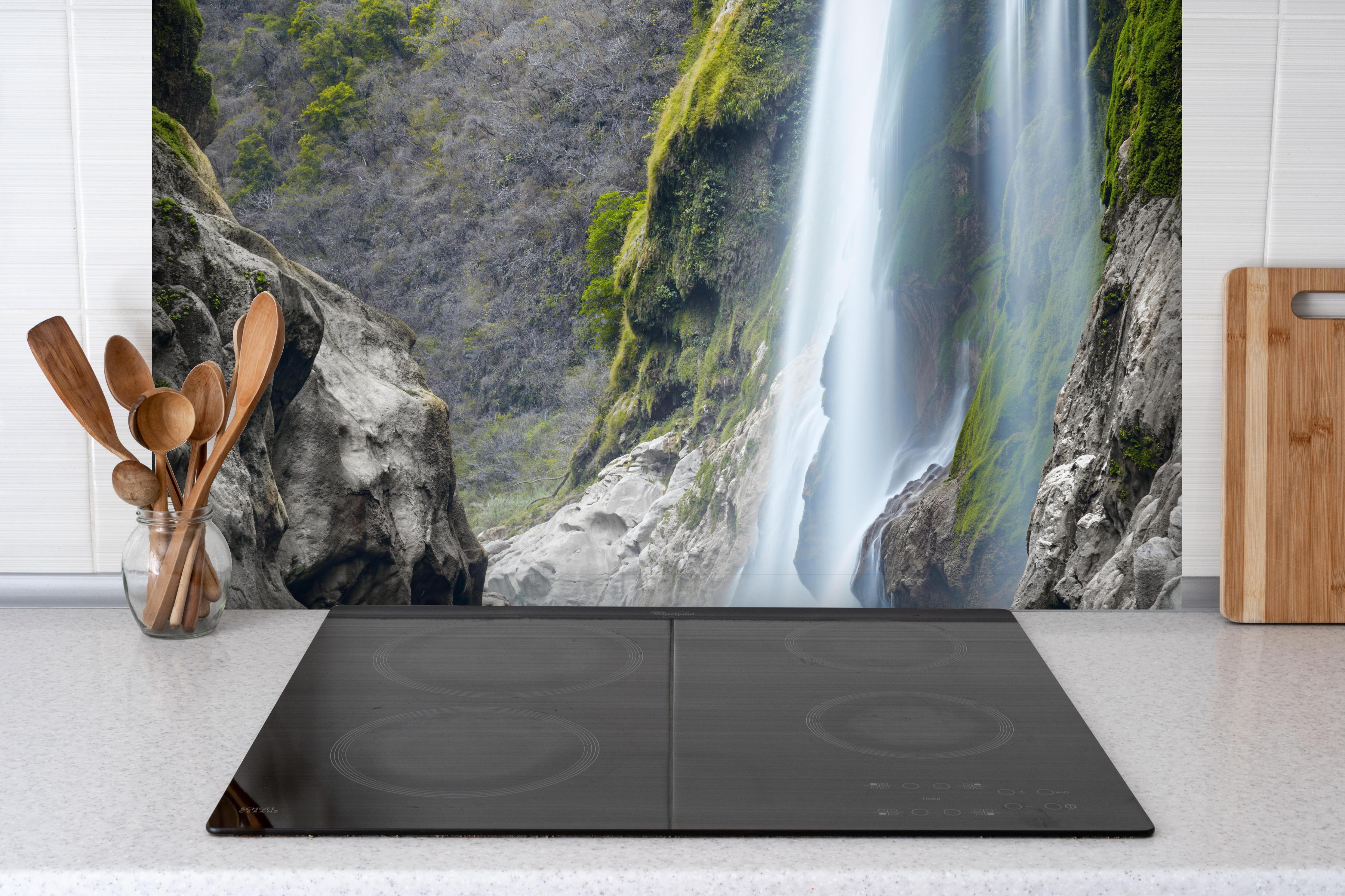 Spritzschutz - Tamul-Wasserfall am Fluss Tampaon hinter einem Cerankochfeld zwischen Holz-Kochutensilien