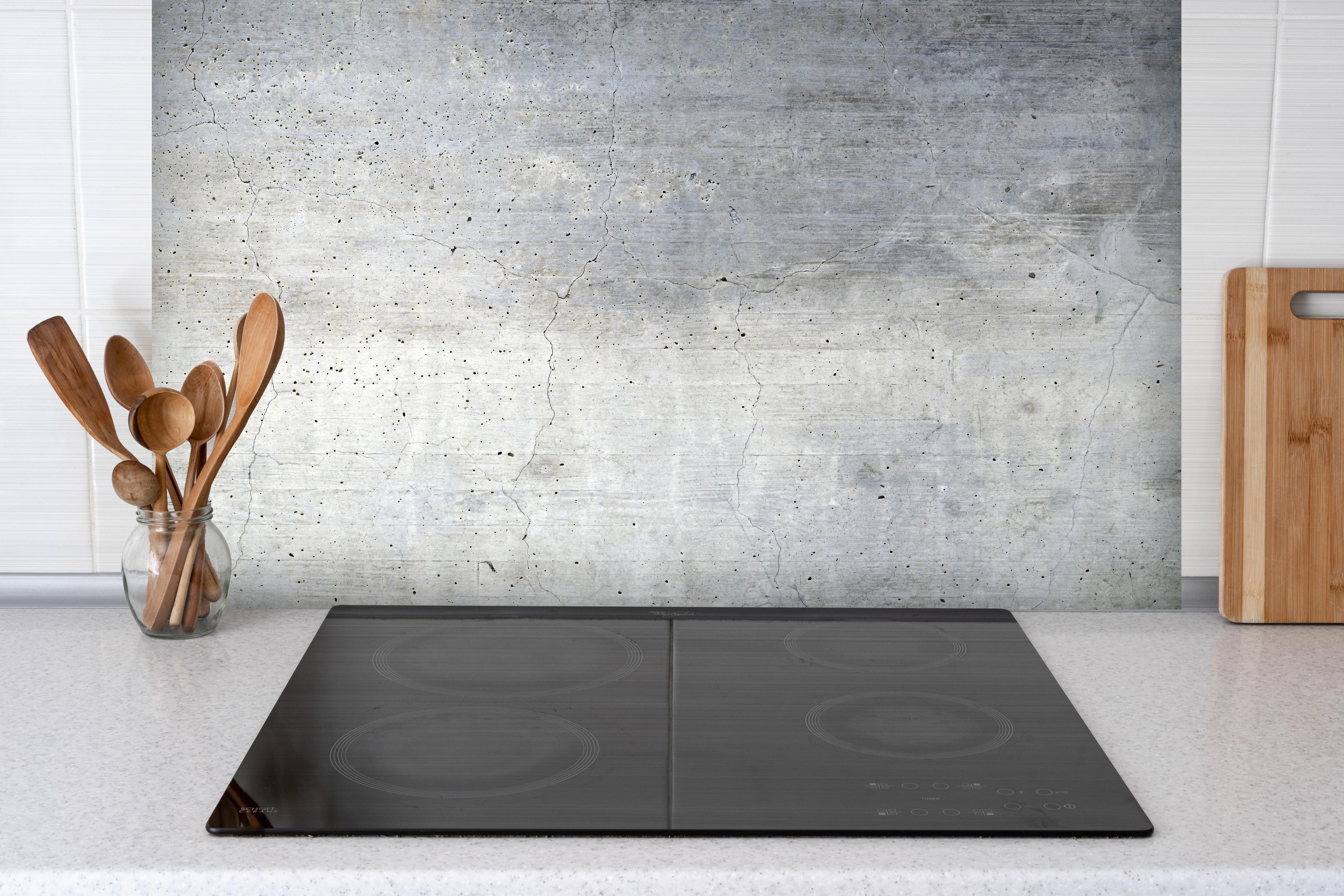 Spritzschutz - Textur einer alten grauen Betonwand hinter einem Cerankochfeld zwischen Holz-Kochutensilien