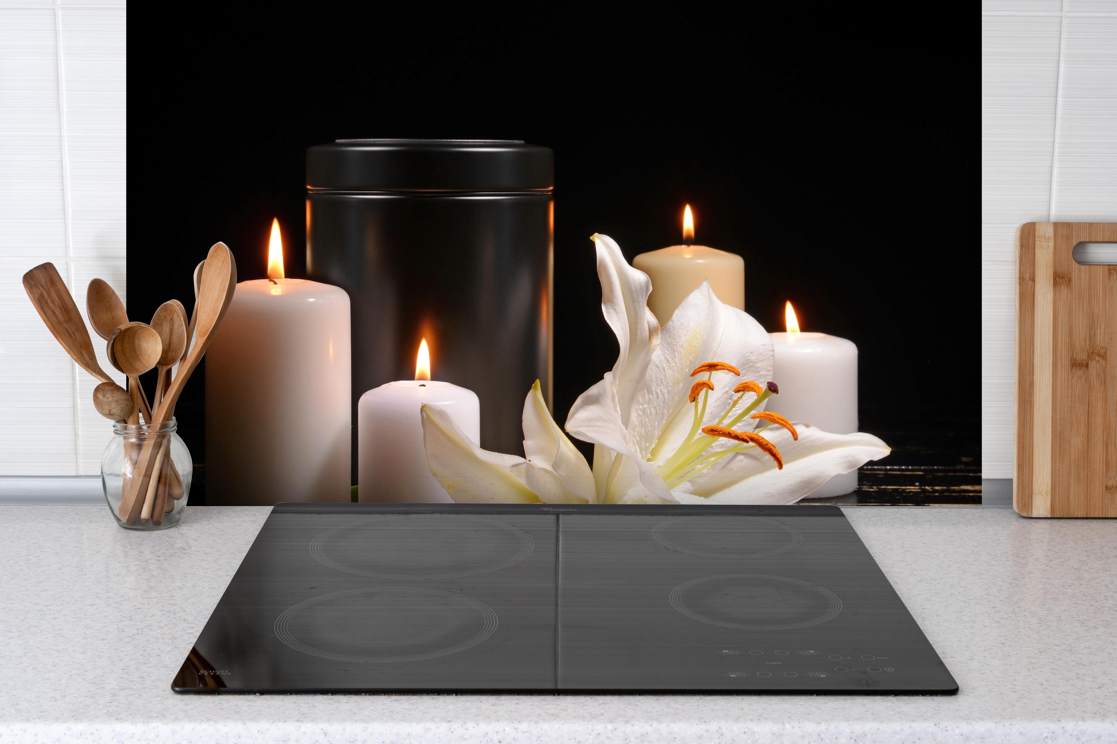 Spritzschutz - Totenurne mit Kerzen und Blume hinter einem Cerankochfeld zwischen Holz-Kochutensilien