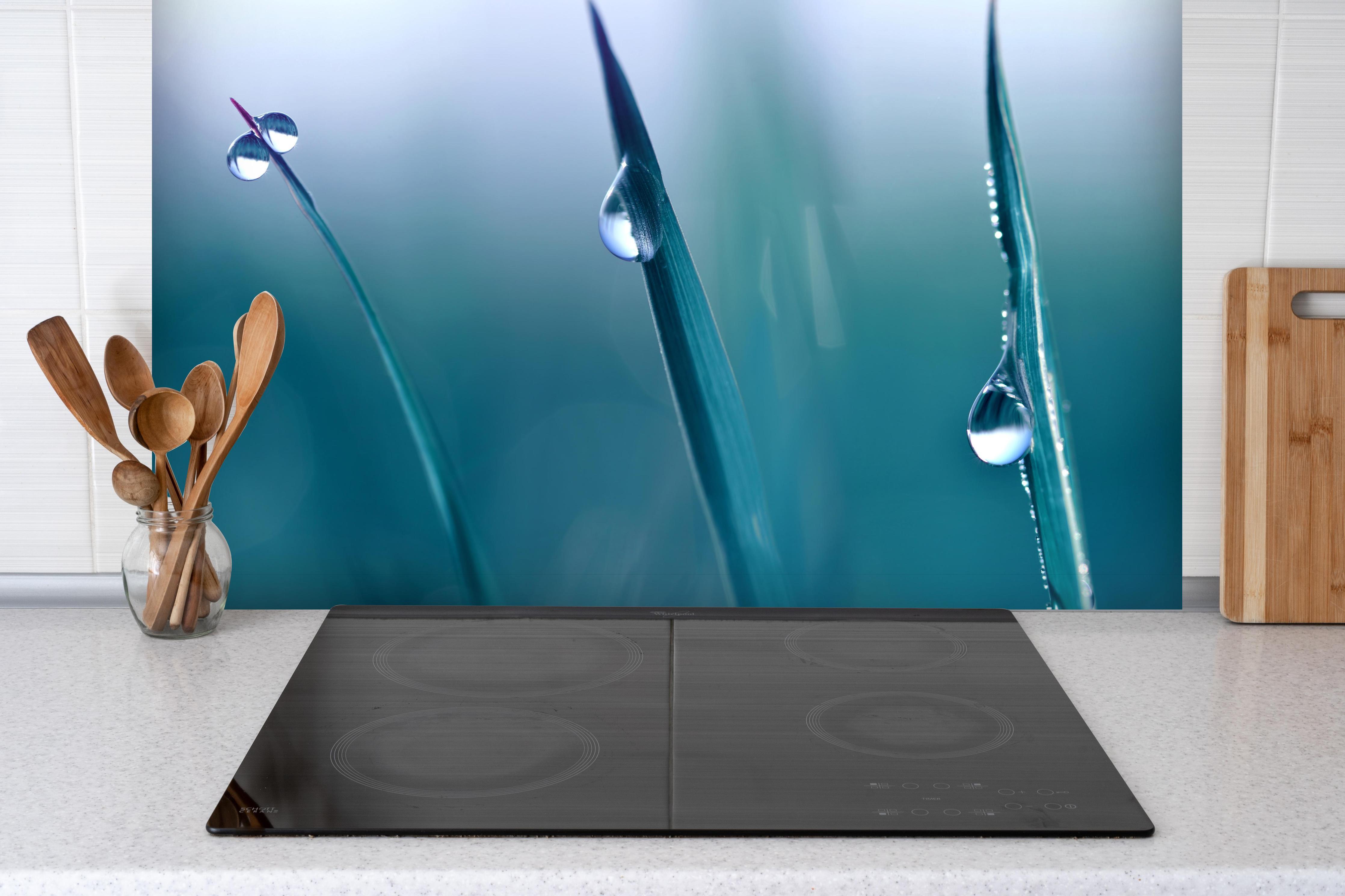 Spritzschutz - Transparente Tautropfen hinter einem Cerankochfeld zwischen Holz-Kochutensilien