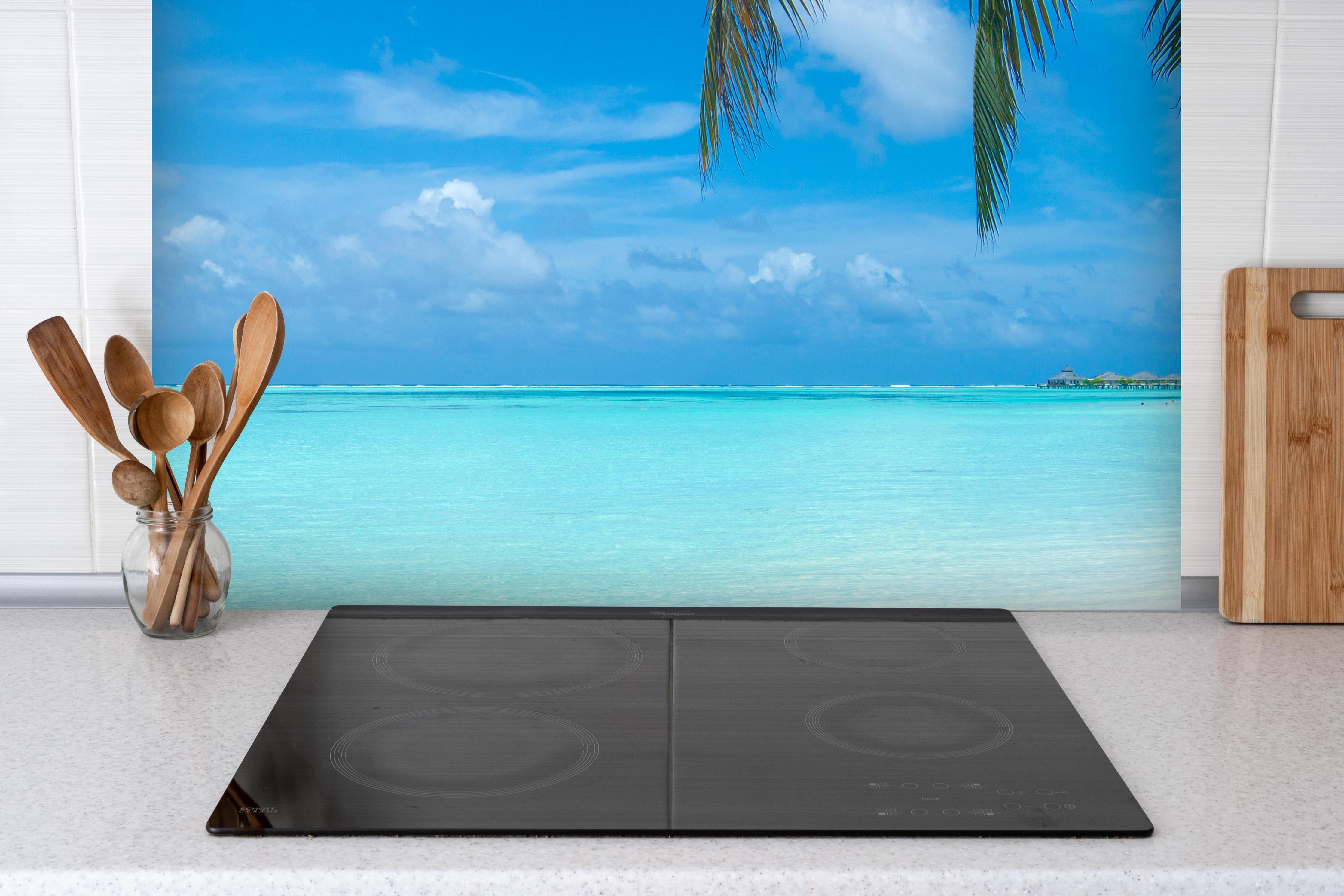 Spritzschutz - Tropische Malediveninsel mit weißem Sandstrand hinter einem Cerankochfeld zwischen Holz-Kochutensilien