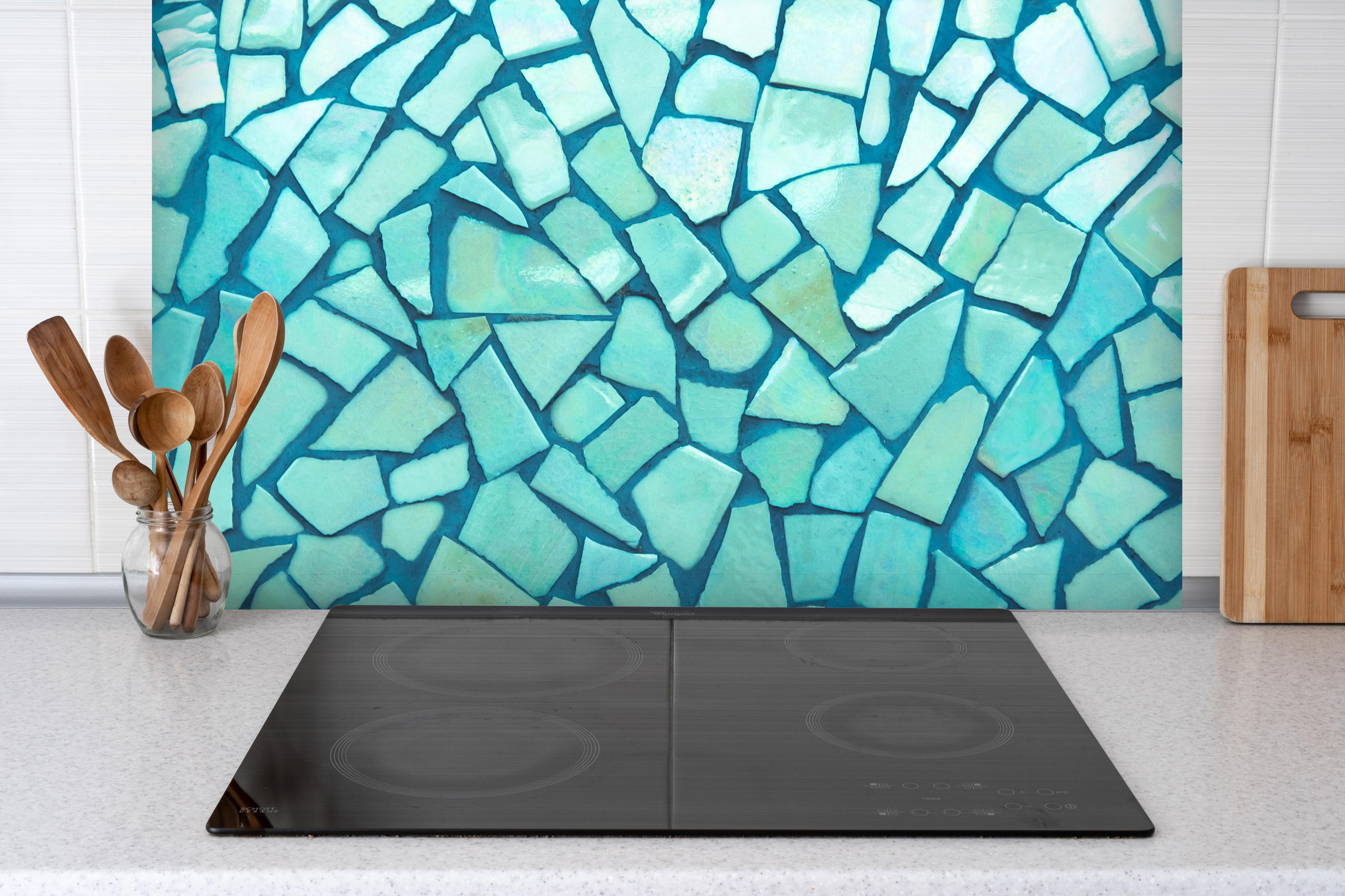 Spritzschutz - Türkise Fliesen Mosaik hinter einem Cerankochfeld zwischen Holz-Kochutensilien