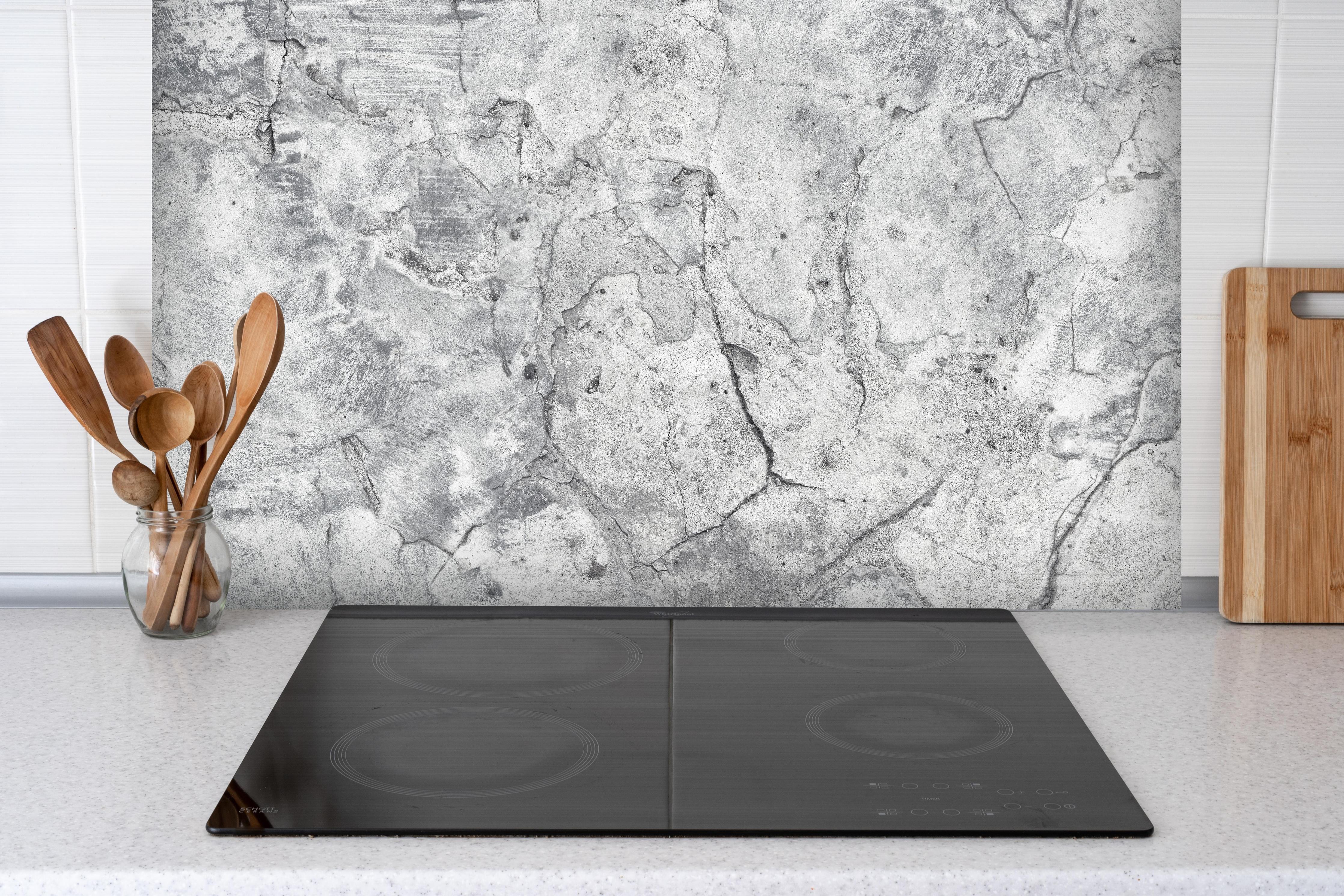 Spritzschutz - Veraltete hellgraue Betonwand hinter einem Cerankochfeld zwischen Holz-Kochutensilien