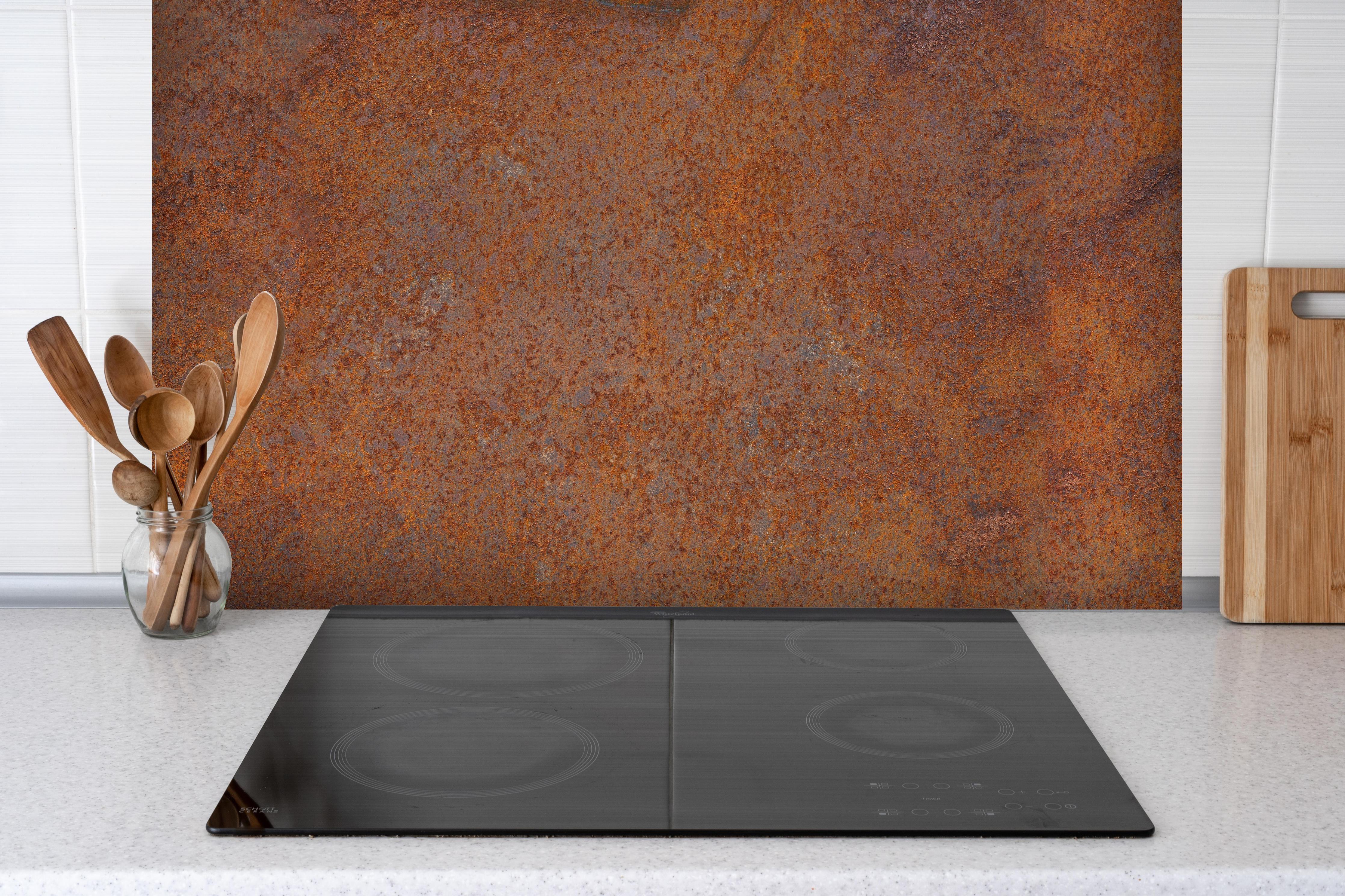 Spritzschutz - Verrostetes Metall hinter einem Cerankochfeld zwischen Holz-Kochutensilien