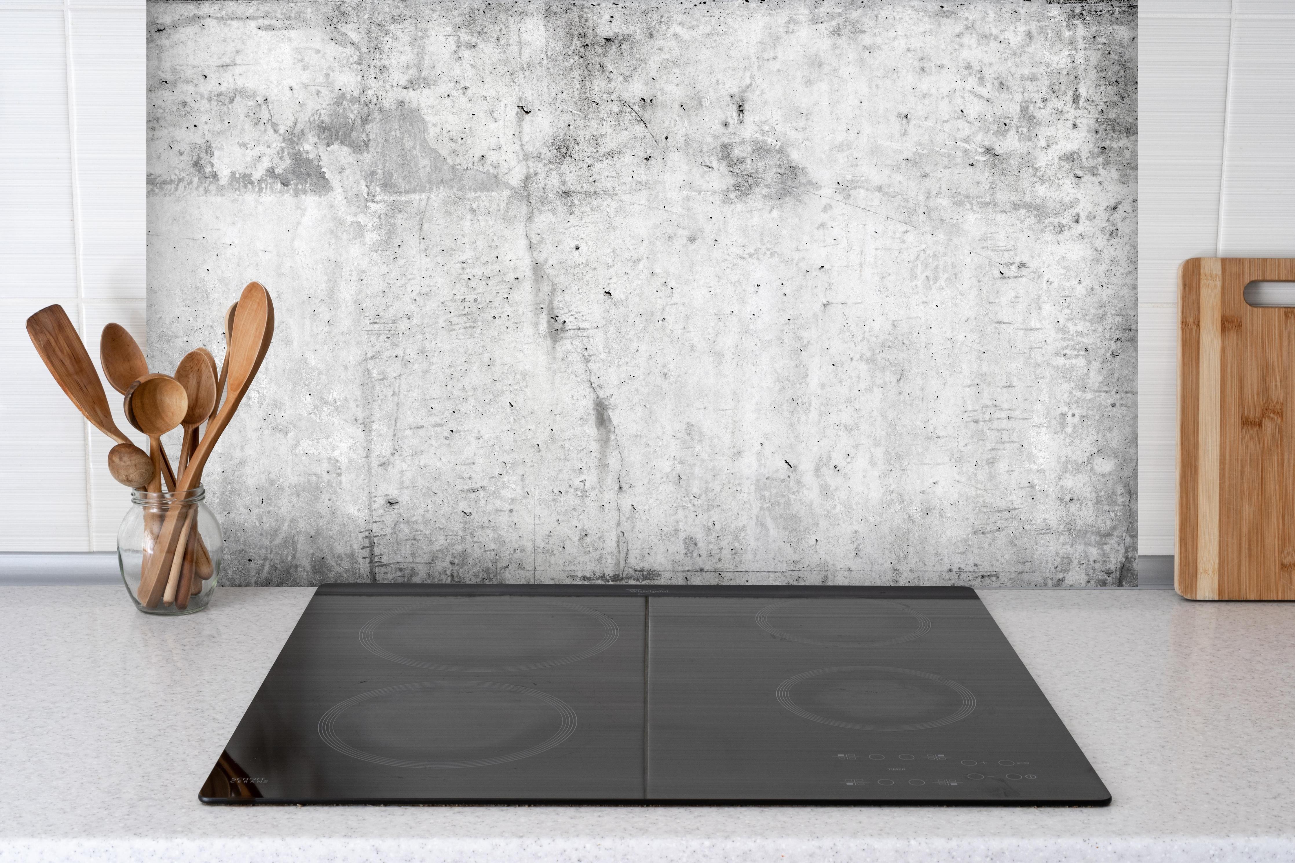 Spritzschutz - Verwitterte weiße Betonwandtextur hinter einem Cerankochfeld zwischen Holz-Kochutensilien