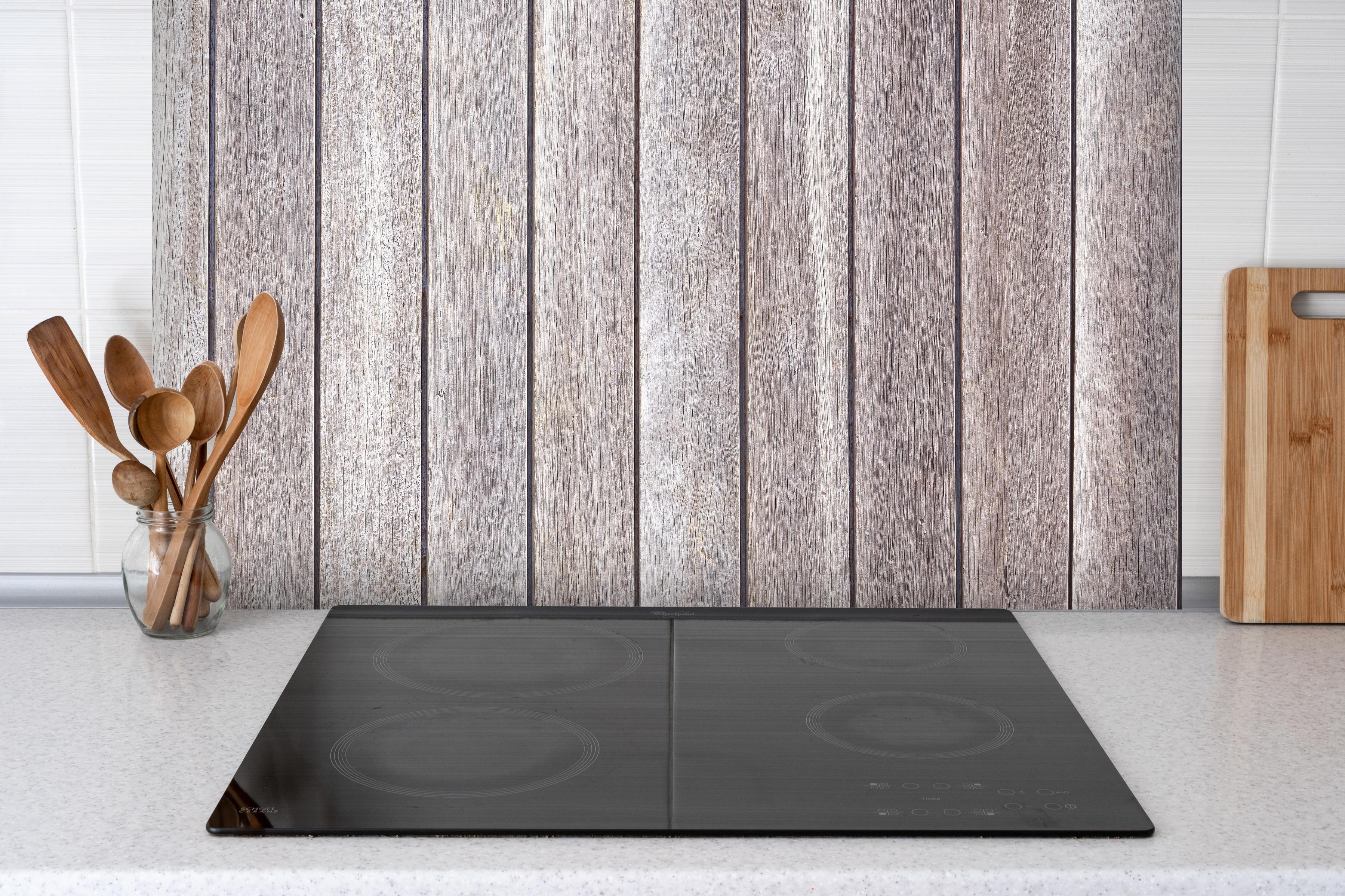 Spritzschutz - Vintage Holzdielenmuster hinter einem Cerankochfeld zwischen Holz-Kochutensilien