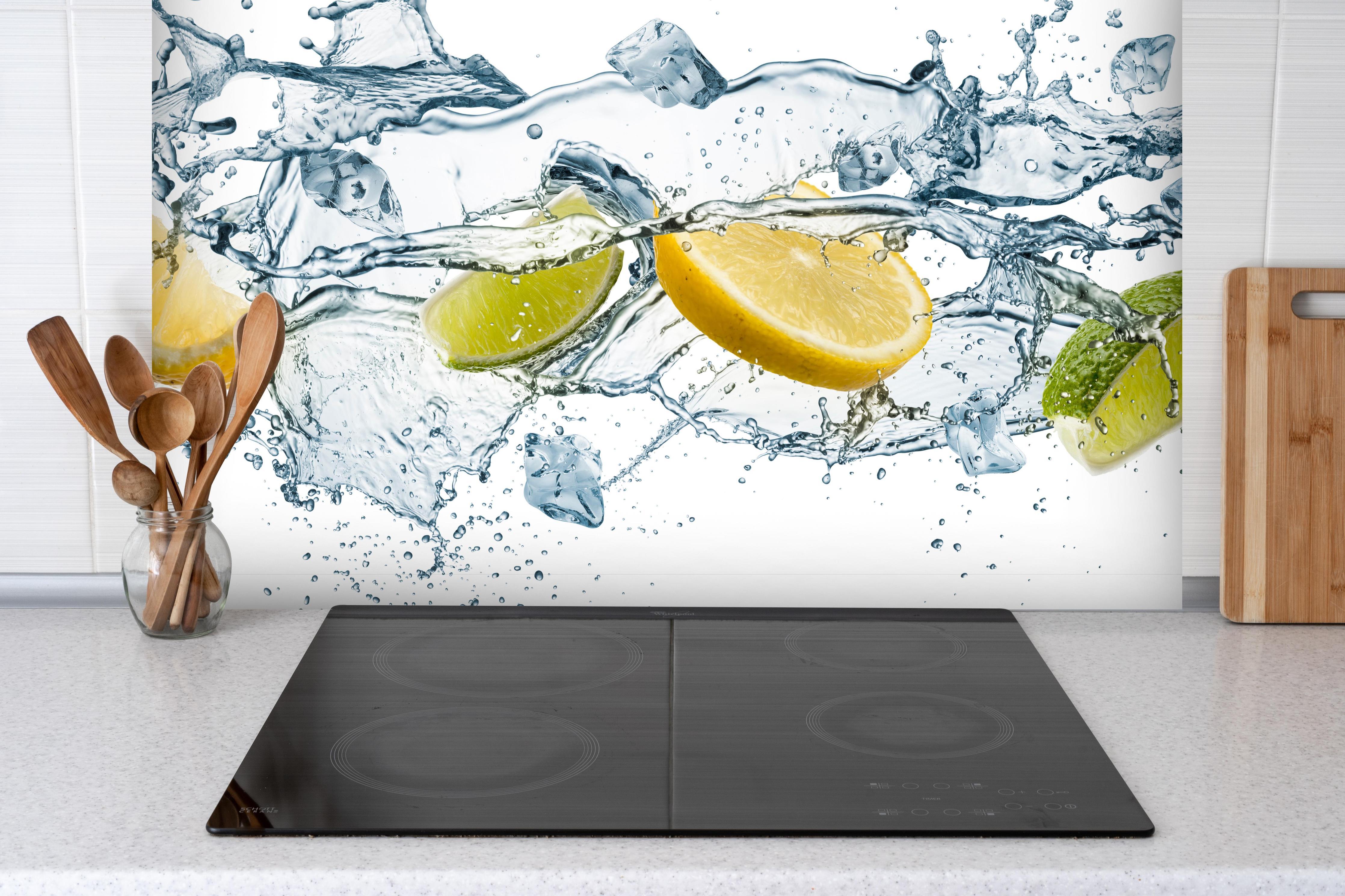 Spritzschutz - Wasser mit Zitrusfrüchten Artwork hinter einem Cerankochfeld zwischen Holz-Kochutensilien