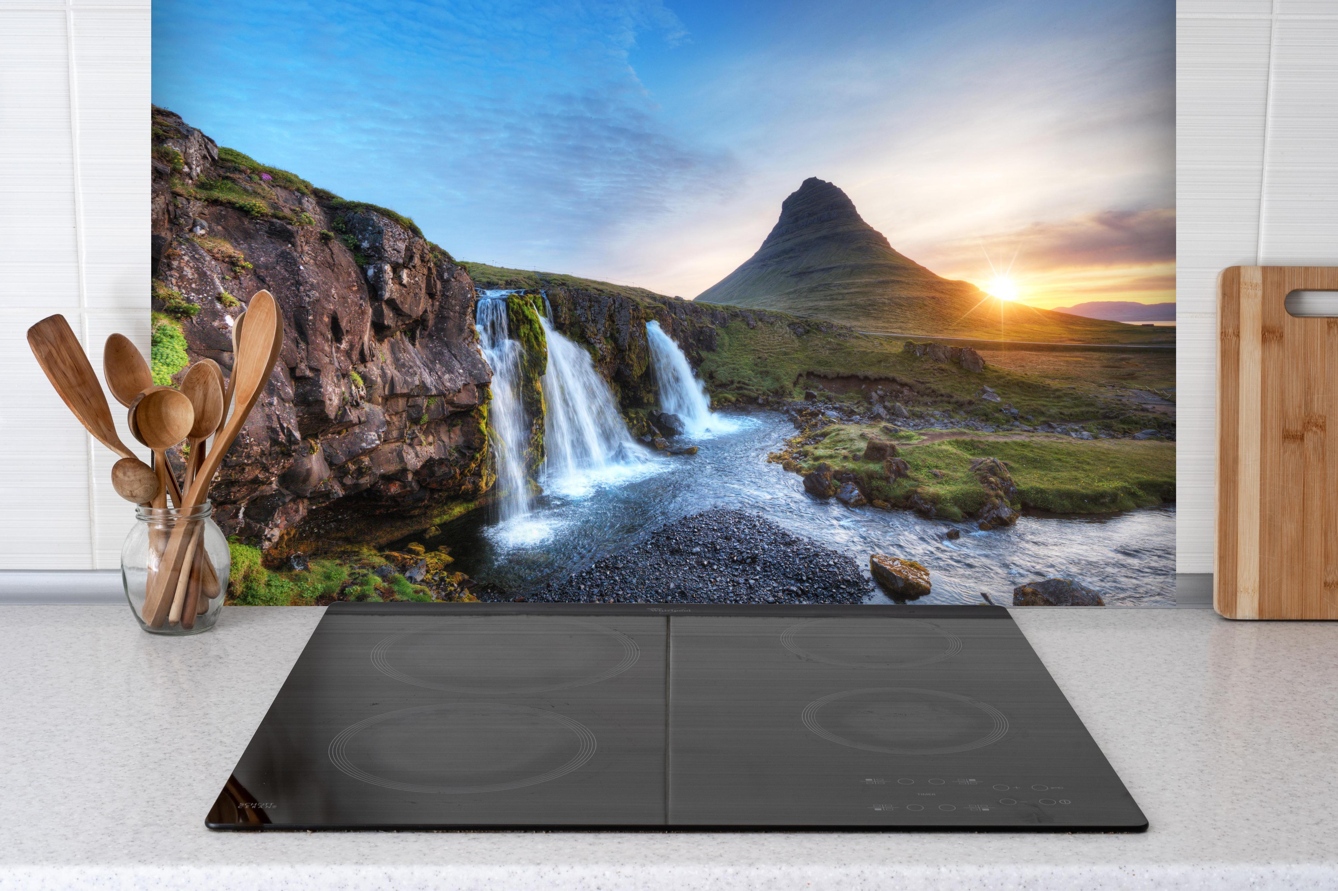 Spritzschutz - Wasserfall bei Sonnenuntergang hinter einem Cerankochfeld zwischen Holz-Kochutensilien