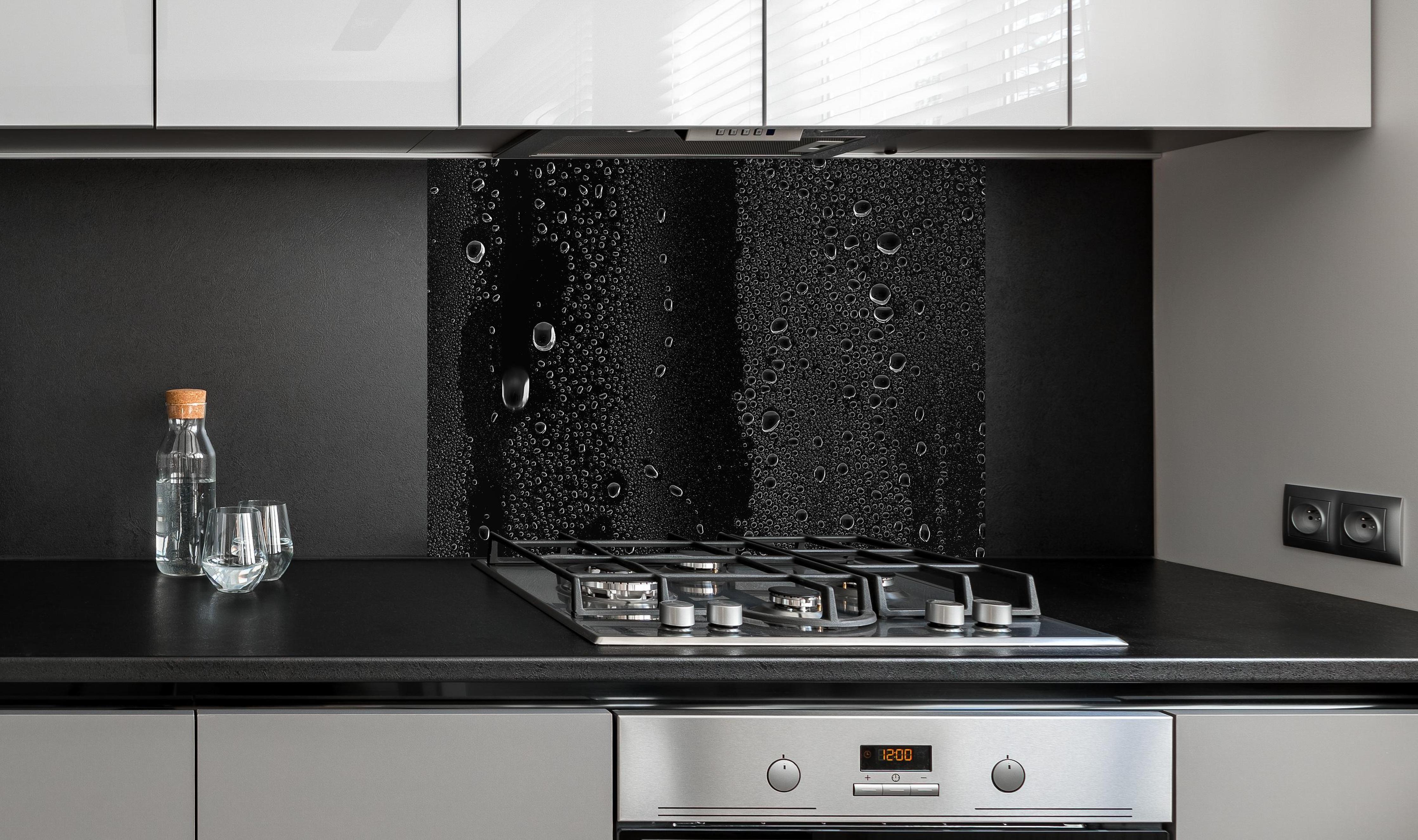 Spritzschutz - Wassertropfen auf schwarzem Glas an edler Anthrazit-Wand hinter silbernem Gasherd