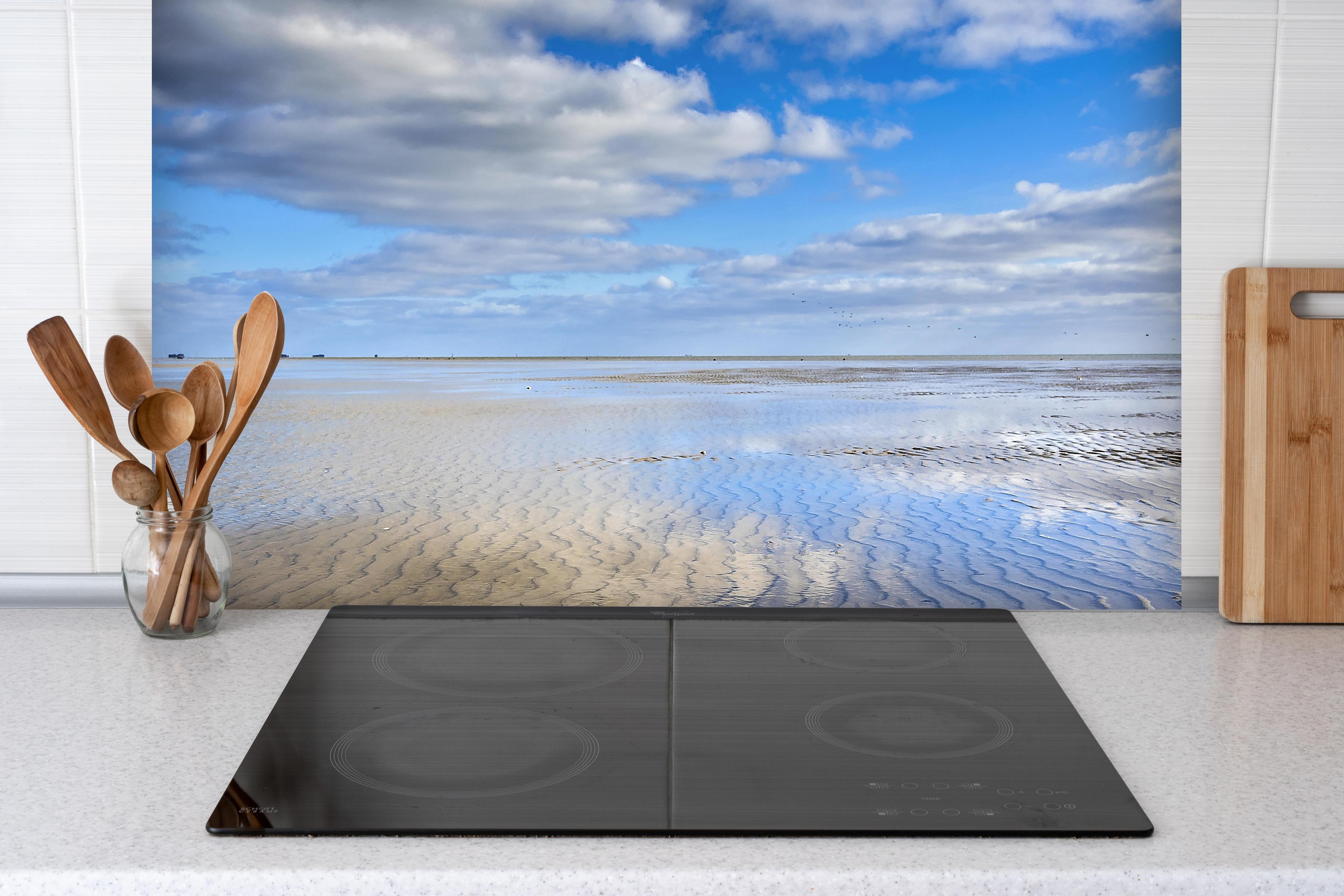 Spritzschutz - Wattenmeer der Nordsee bei Ebbe hinter einem Cerankochfeld zwischen Holz-Kochutensilien