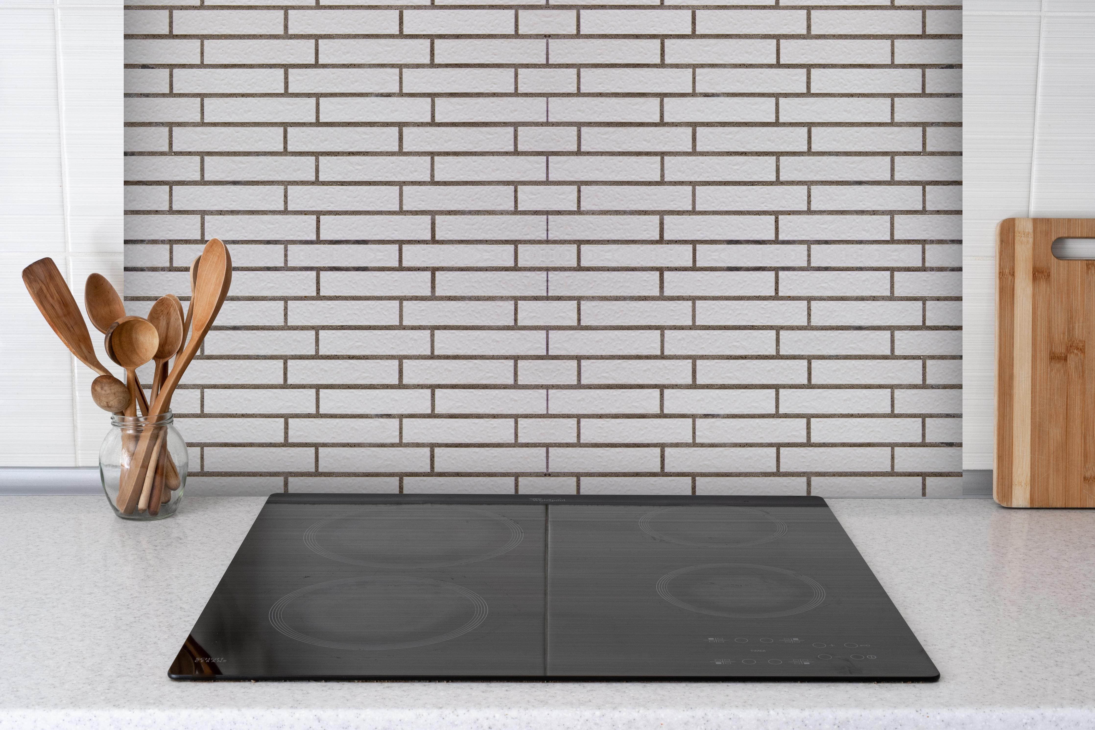 Spritzschutz - Weiß-Brauner Backsteinmauer hinter einem Cerankochfeld zwischen Holz-Kochutensilien