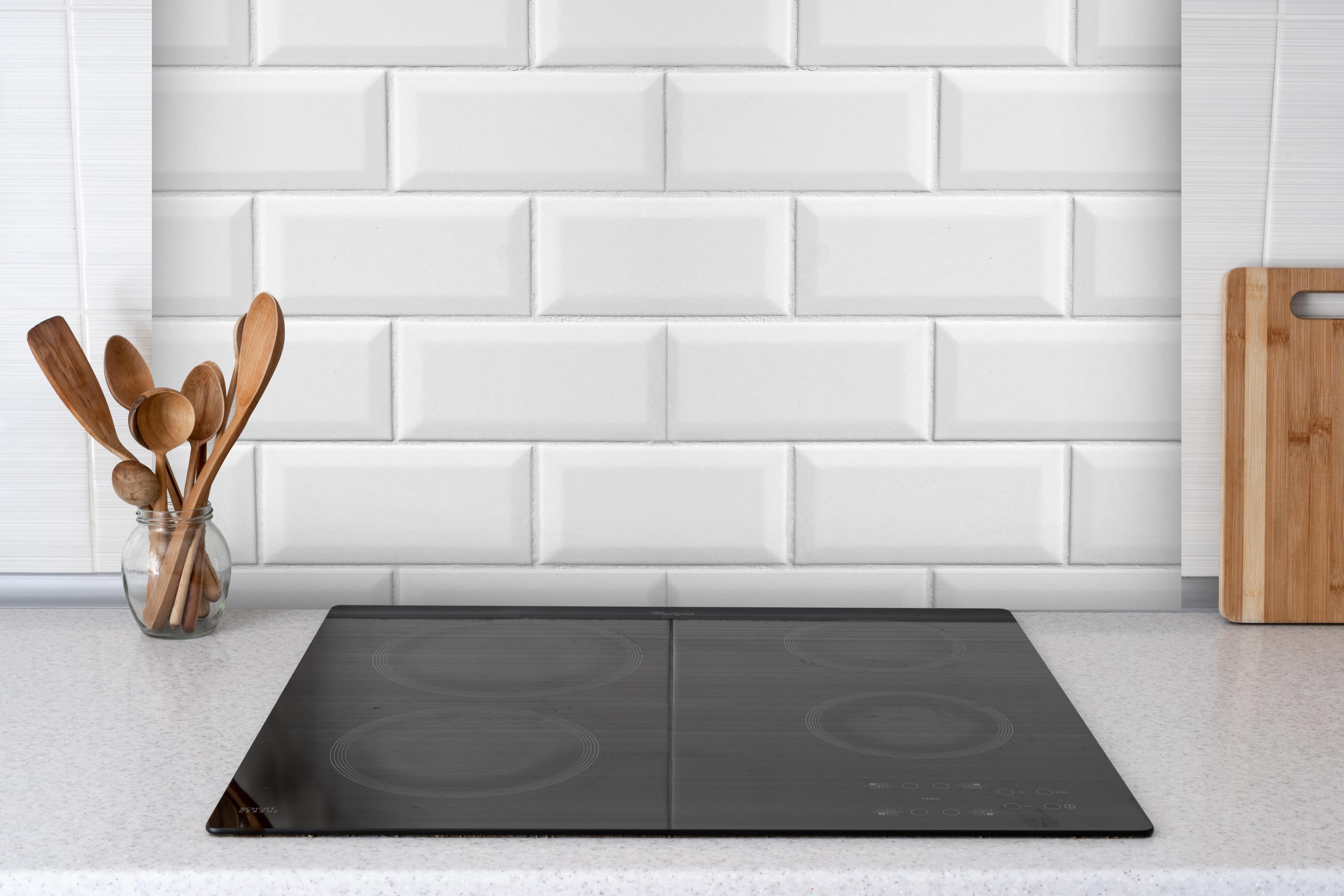Spritzschutz - Weiße Fliesen Fliesenspiegel hinter einem Cerankochfeld zwischen Holz-Kochutensilien