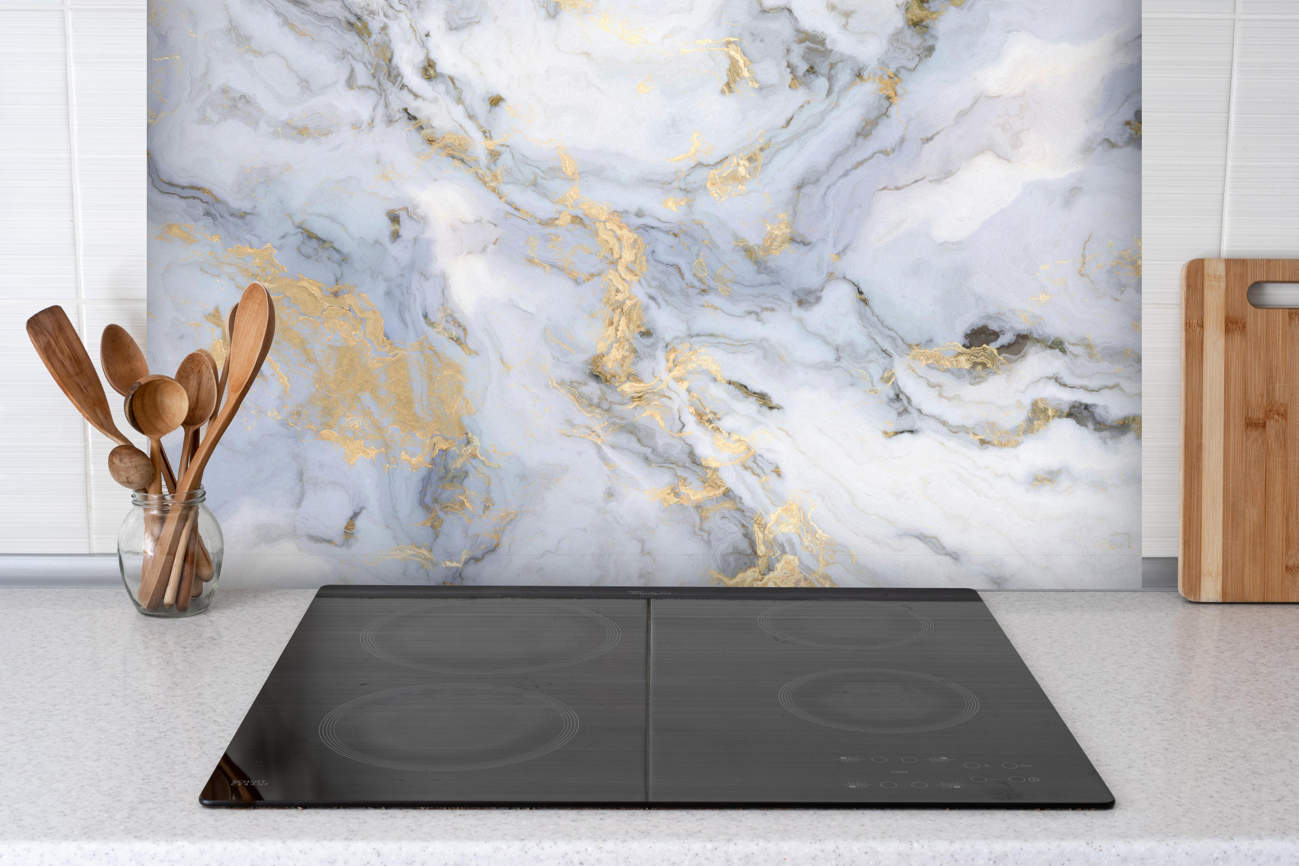 Spritzschutz - Weißer Marmor mit Goldelementen hinter einem Cerankochfeld zwischen Holz-Kochutensilien